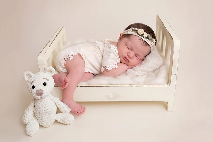 Newborn photo of baby in crib with a handmade crochet bear by Alyssa Renee Photography