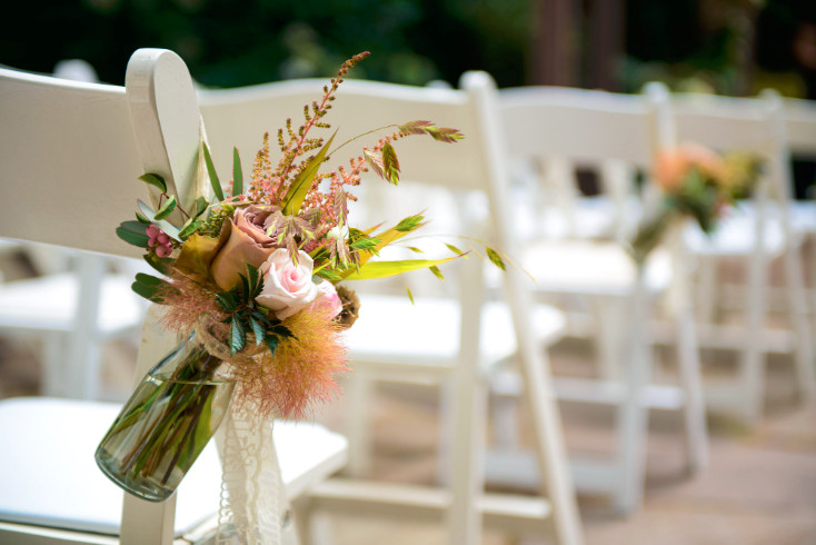 hanging flowers on white wedding chairs