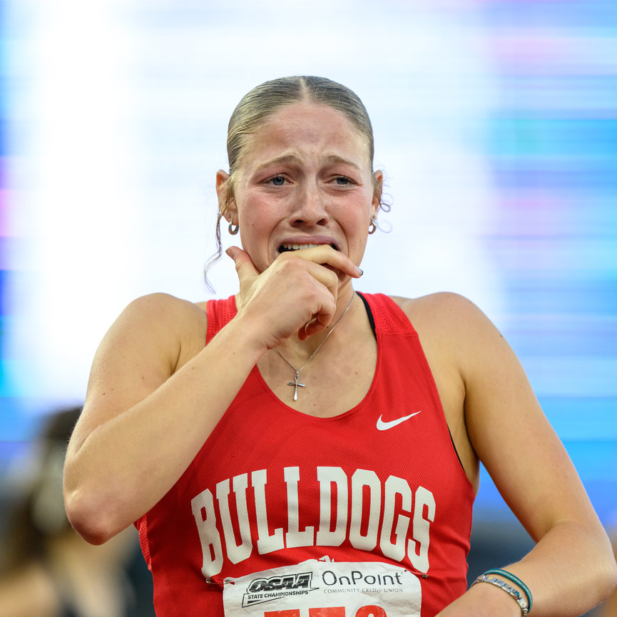 Athlete in a red Bulldogs uniform looking emotional at a sports event.