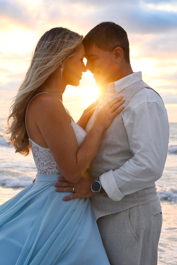 Couple embracing at sunset on the beach, with soft waves and a romantic atmosphere.