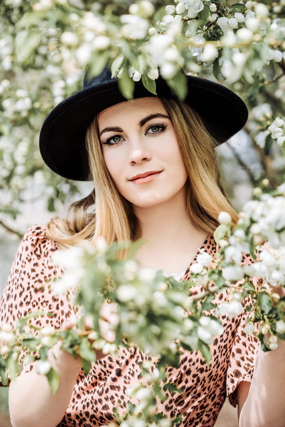 Senior portrait of a girl in a tree with white flowers wearing a dress and a hat in Wayzata Minnesota
