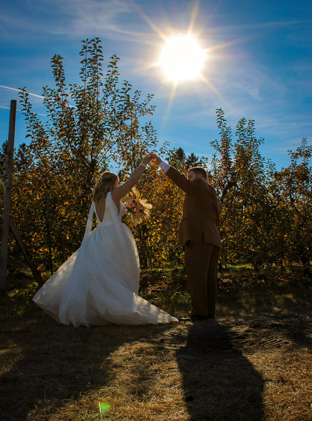 Bride and groom silhouetted in an orchard at sunset