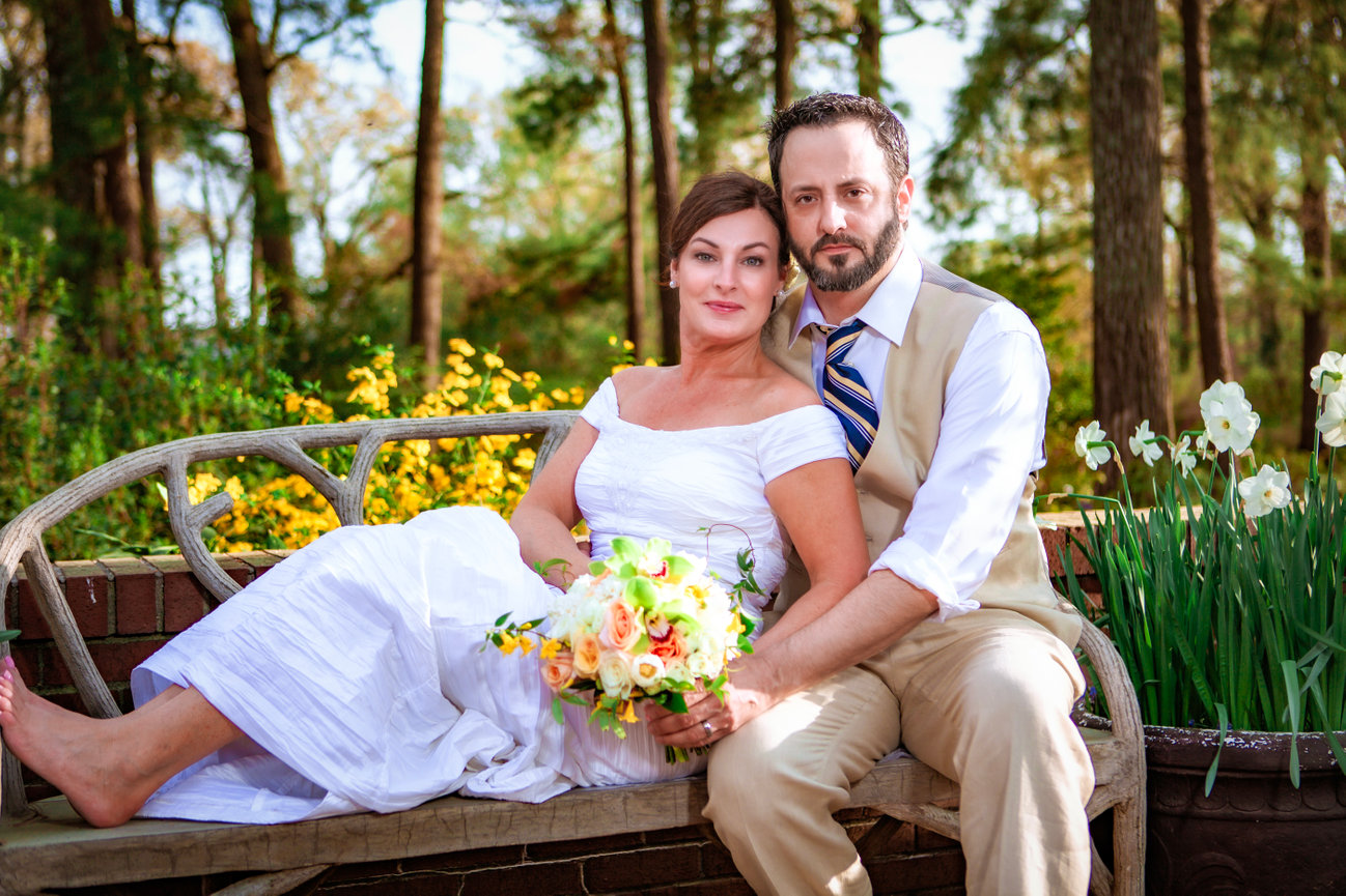 Bride and groom seated together on a garden bench surrounded by spring flowers during their intimate micro wedding. captured by gulf coast photographer Dixon Creative Images