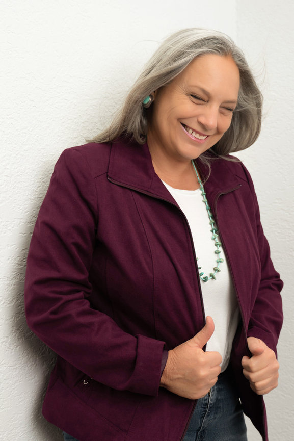 Smiling woman in burgundy jacket, hand on hip for attorney branding photo.