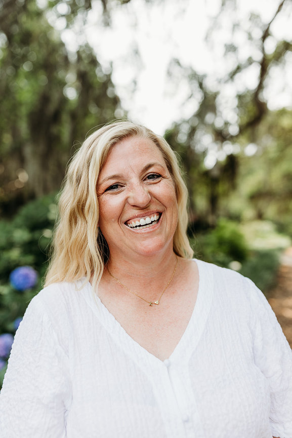 A blond woman in a white shirt smiles at the camera