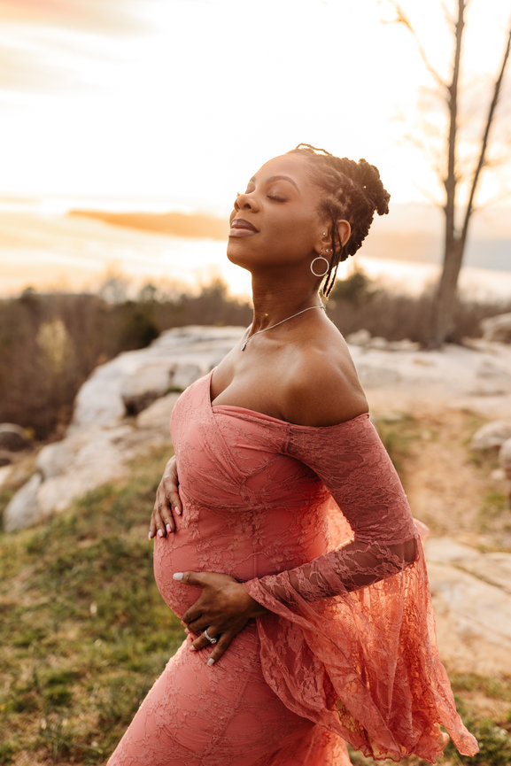 a Black pregnant woman caresses her belly and closes her eyes in a Huntsville, Alabama maternity photoshoot