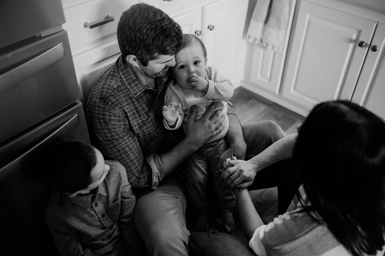 in black and white a family sit on the floor of a kitchen during a Huntsville Alabama family photoshoot