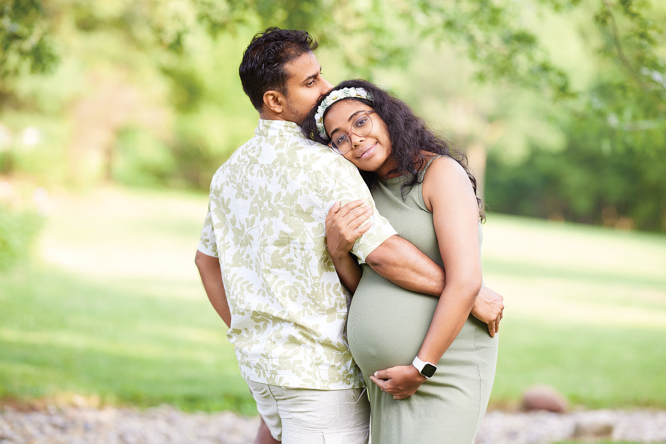 Outdoor portrait of a couple embracing during maternity, captured in soft natural light with a calm, intimate connection and a timeless sense of love