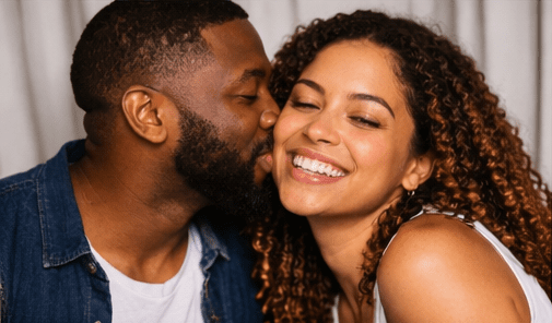 Man giving a cheek kiss to a smiling woman