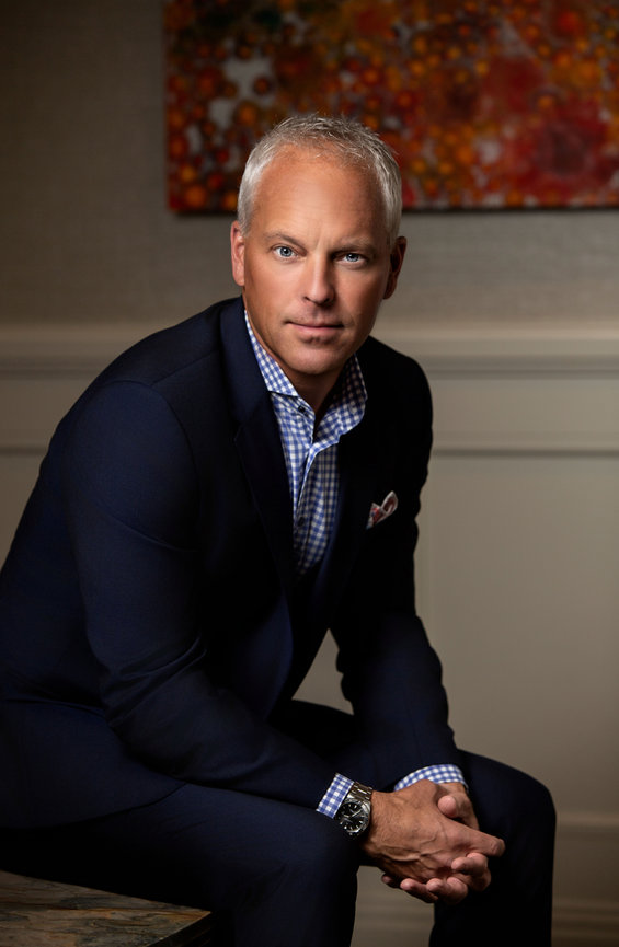 Professional man in a blue suit standing outdoors with arms crossed.