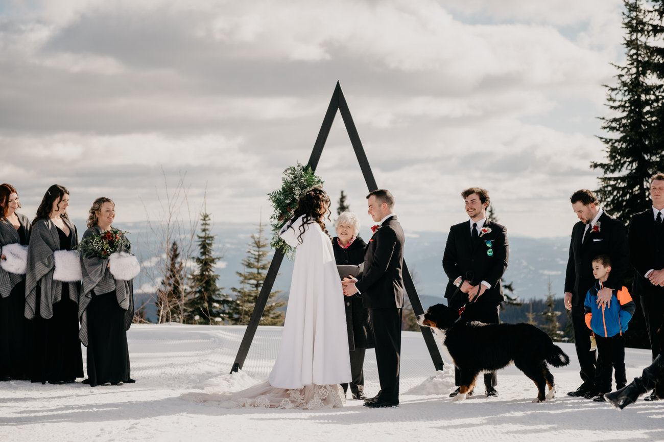 Bride and groom exchange vows during a romantic winter wedding ceremony at a snow-covered Kelowna wedding venue, captured by an Okanagan wedding photographer.