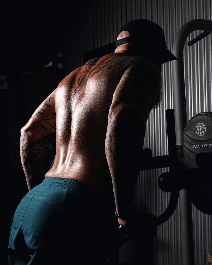 Fitness athlete performing tricep dips, showcasing a muscular and tattooed back, in a gym at Rage Fitness in Lehi, Utah. Captured by Tre Nelson Photo, specializing in fitness and personal branding photography.