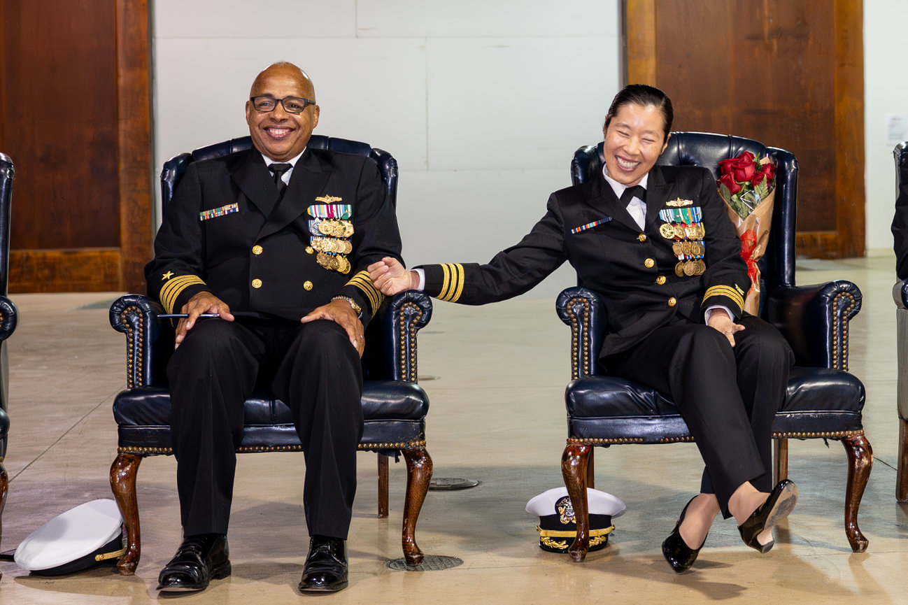 Married Naval Officers at their joint retirement ceremony laughing on stage.jpg