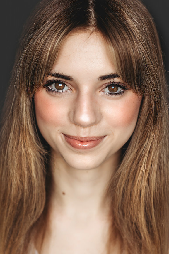 Teenage girl with big brown eyes, blonde hair and rosy cheeks.