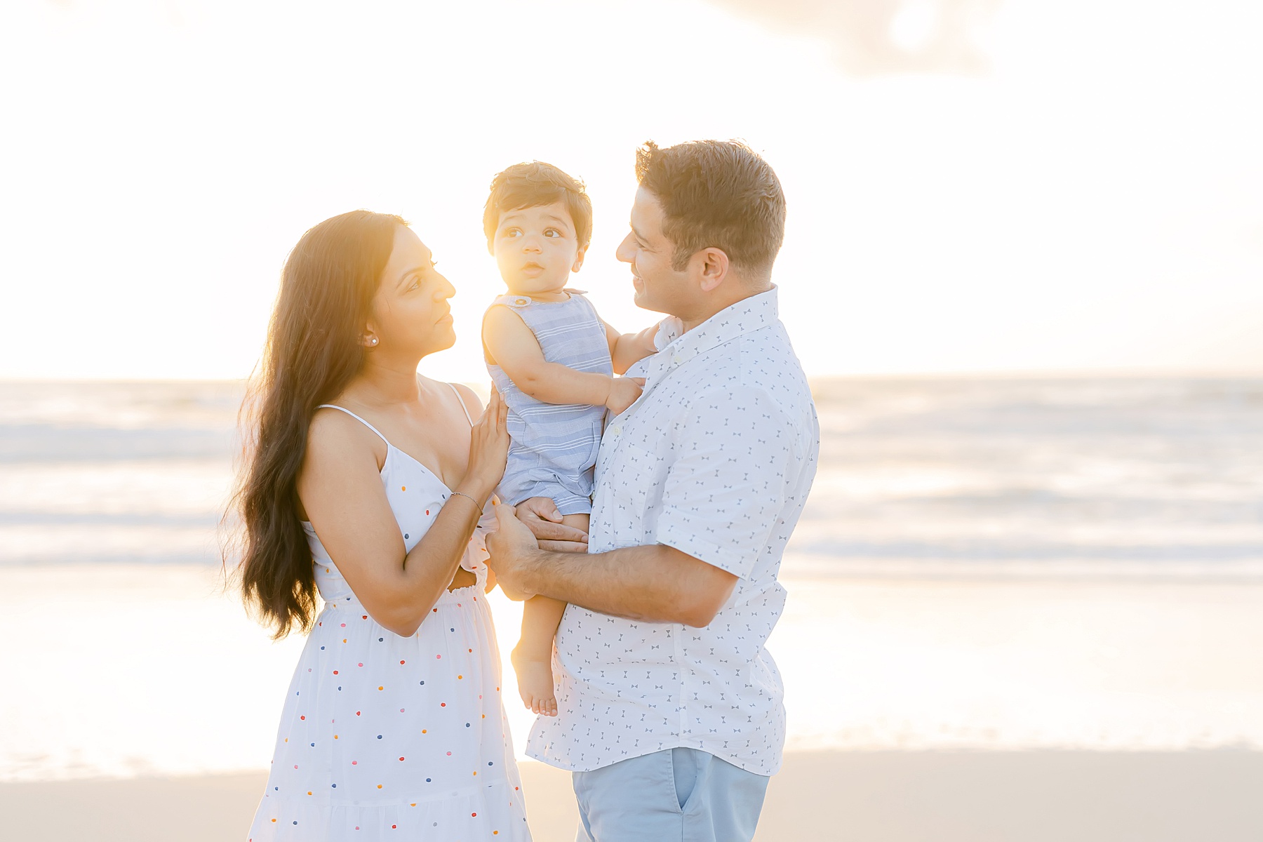 family standing by water at sunrise wearing blue and white and smiling