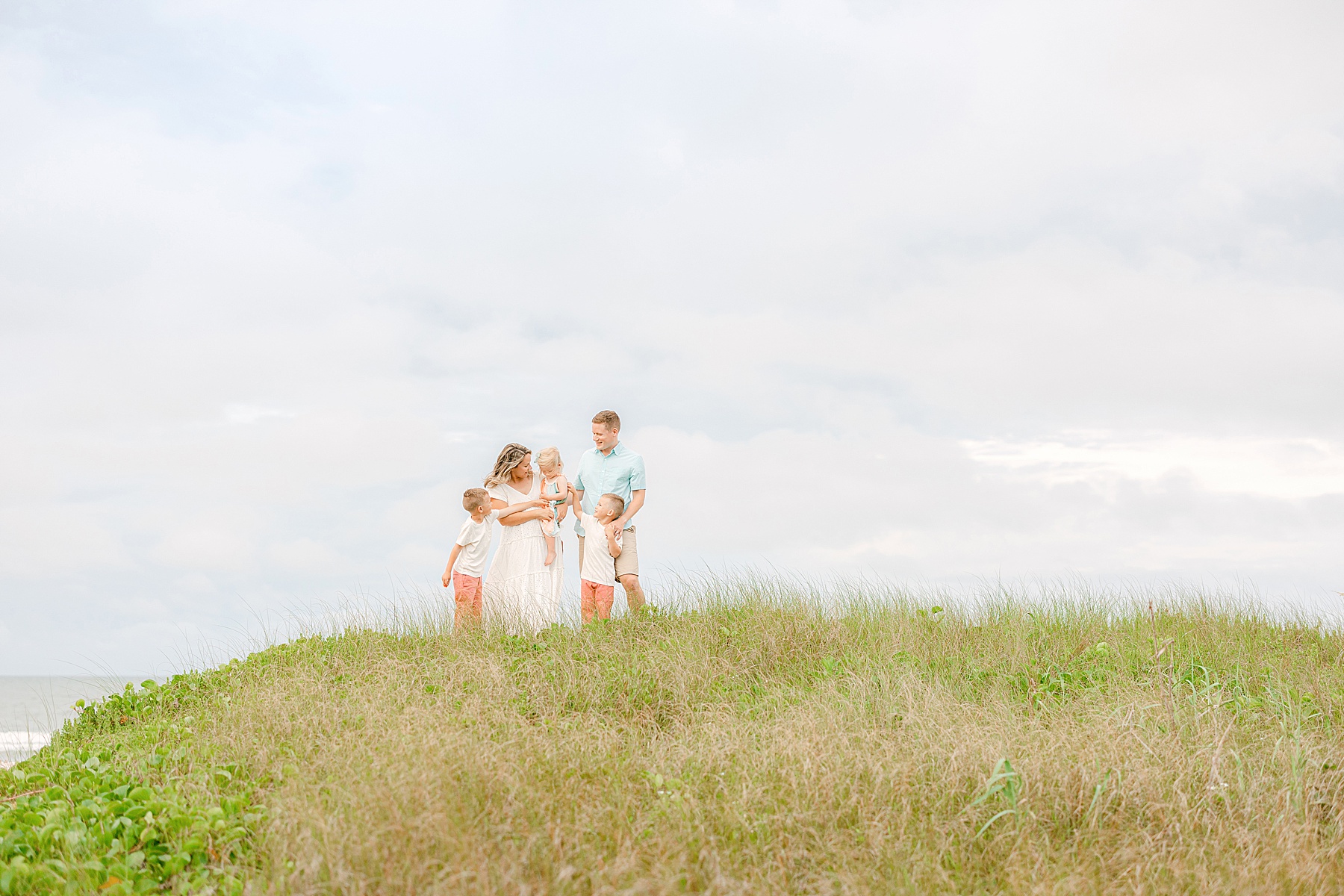 family standing on the grassy dunes at the beach