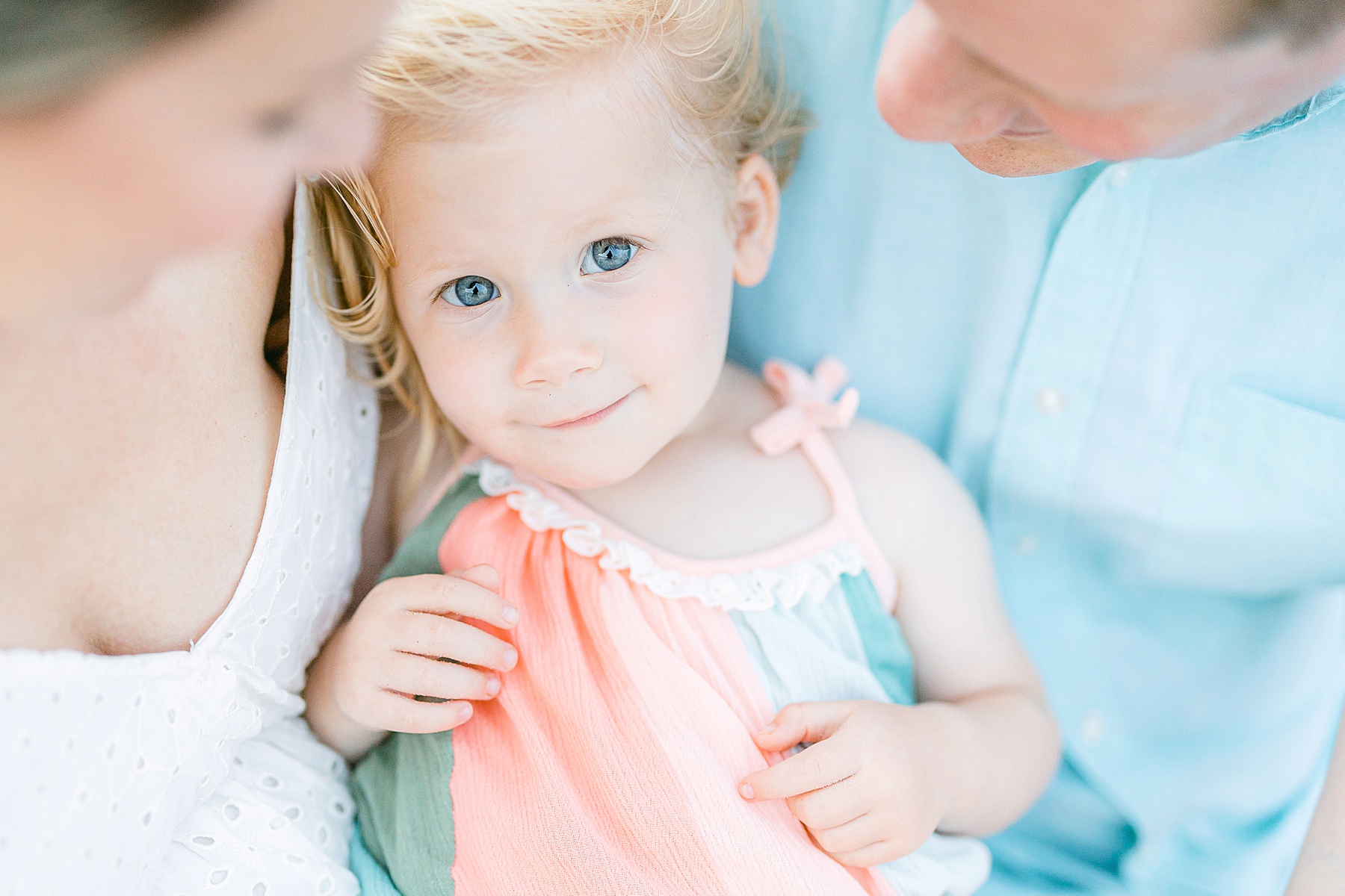 little girl with blue eyes sitting on parents laps