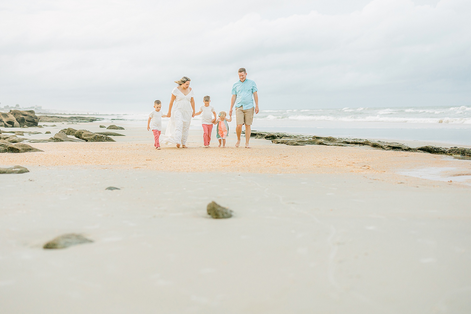 family walking on beach in pastel colors