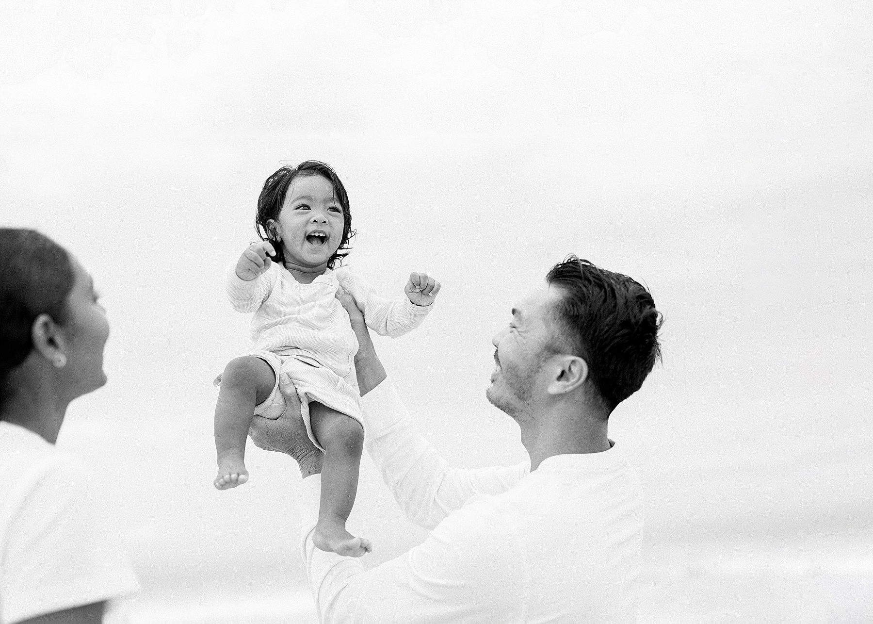 dad throwing baby in the air on the beach