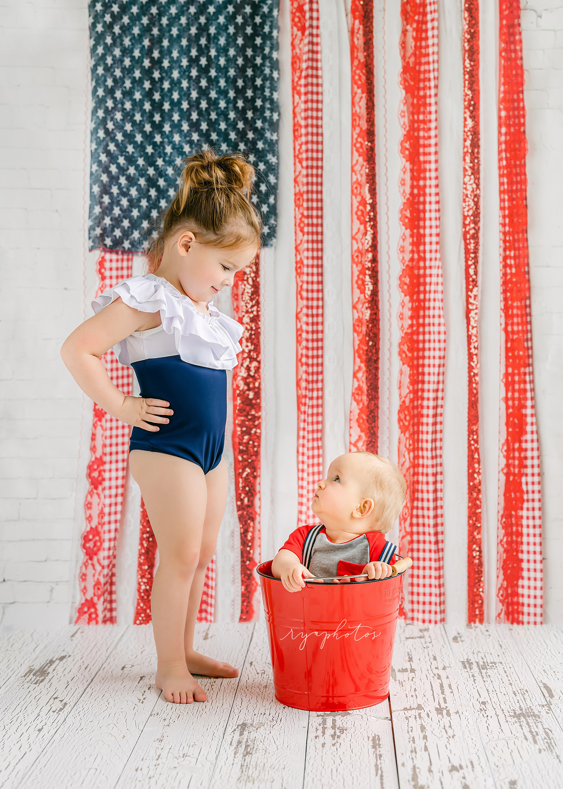 little girl standing in front of baby boy wearing blue and white bathing suit