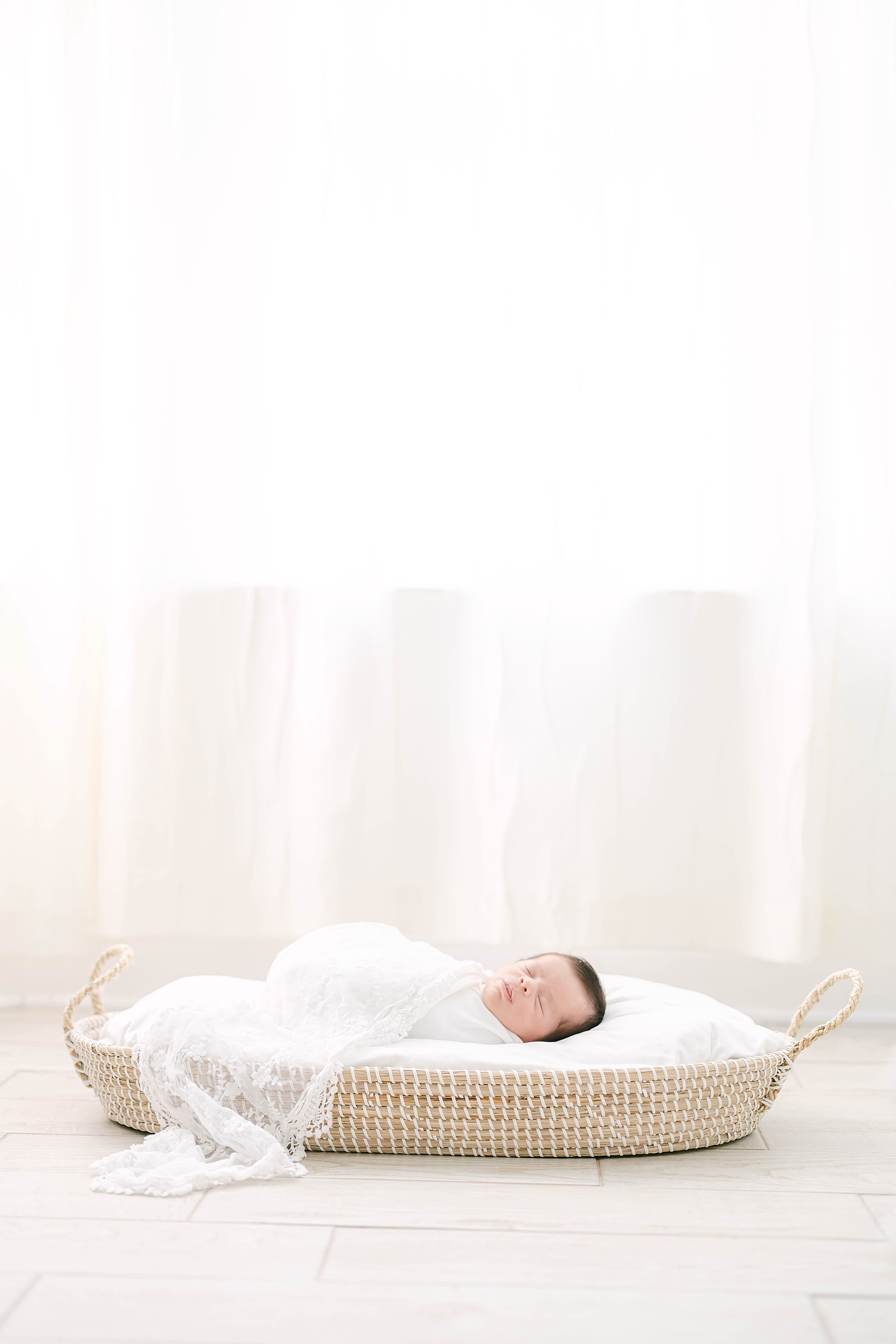 newborn baby in front of window with white wrap