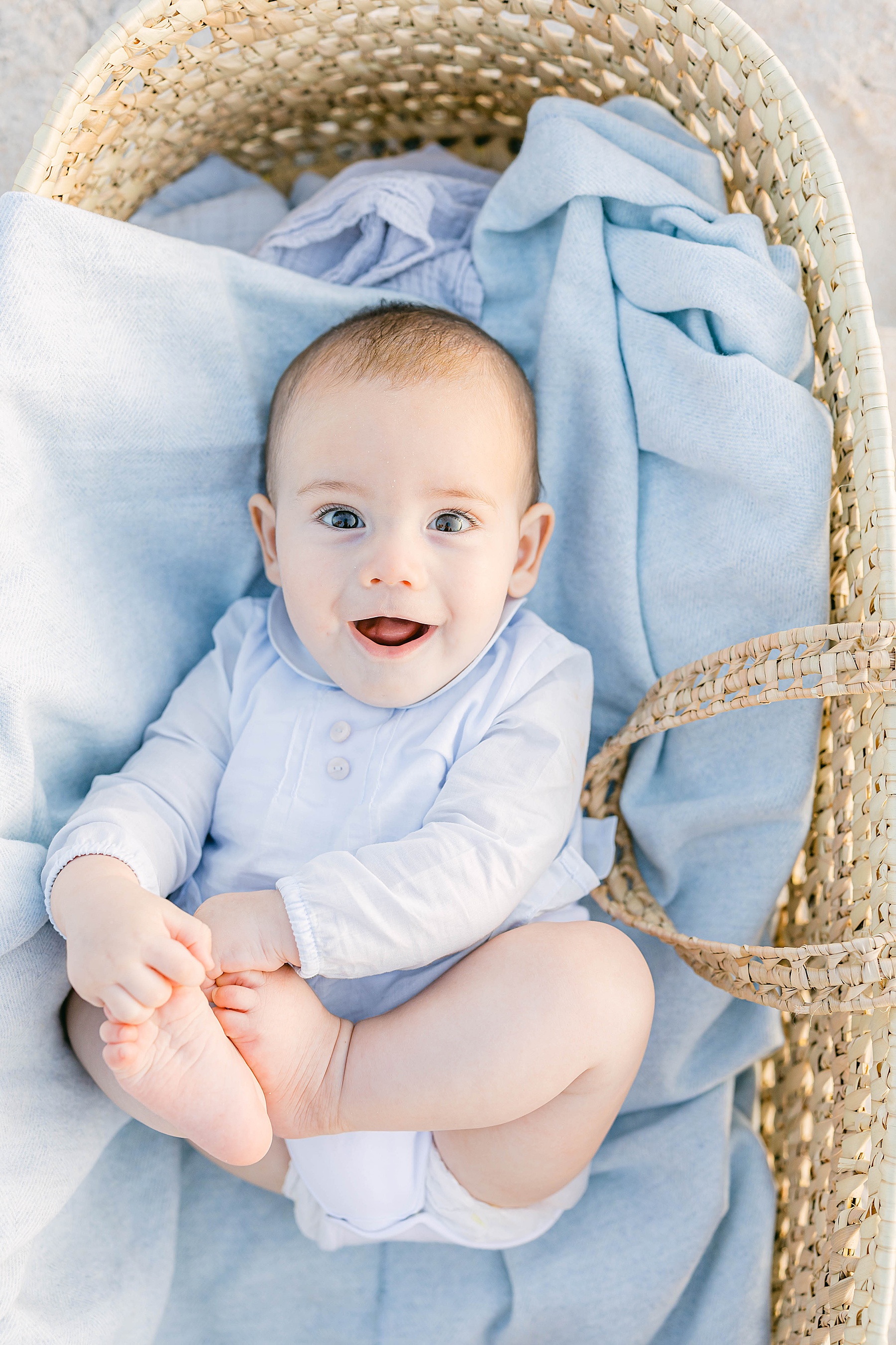 baby boy in basket on the beach with blue blanket