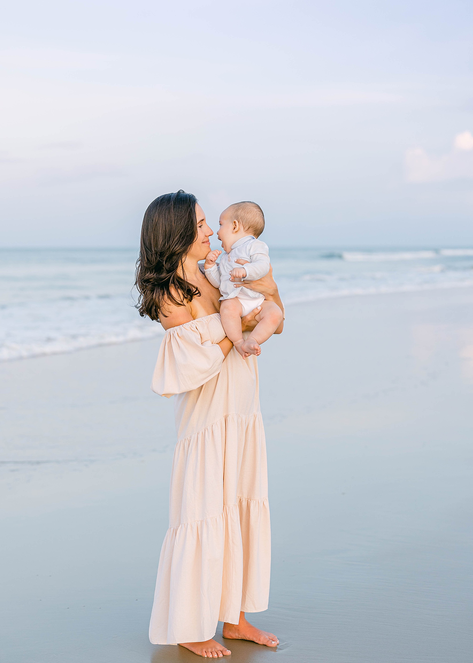 woman holding baby at sunset on the beach