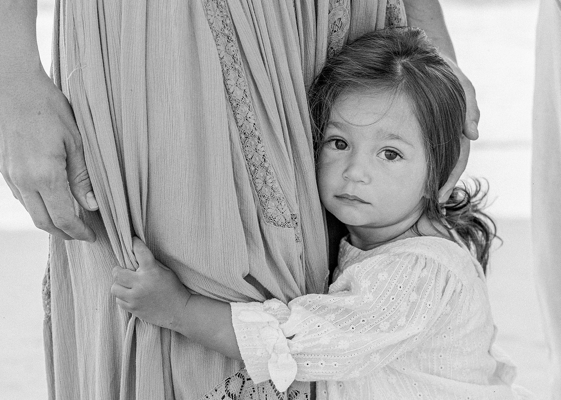 little girl holding on to her mom at the beach