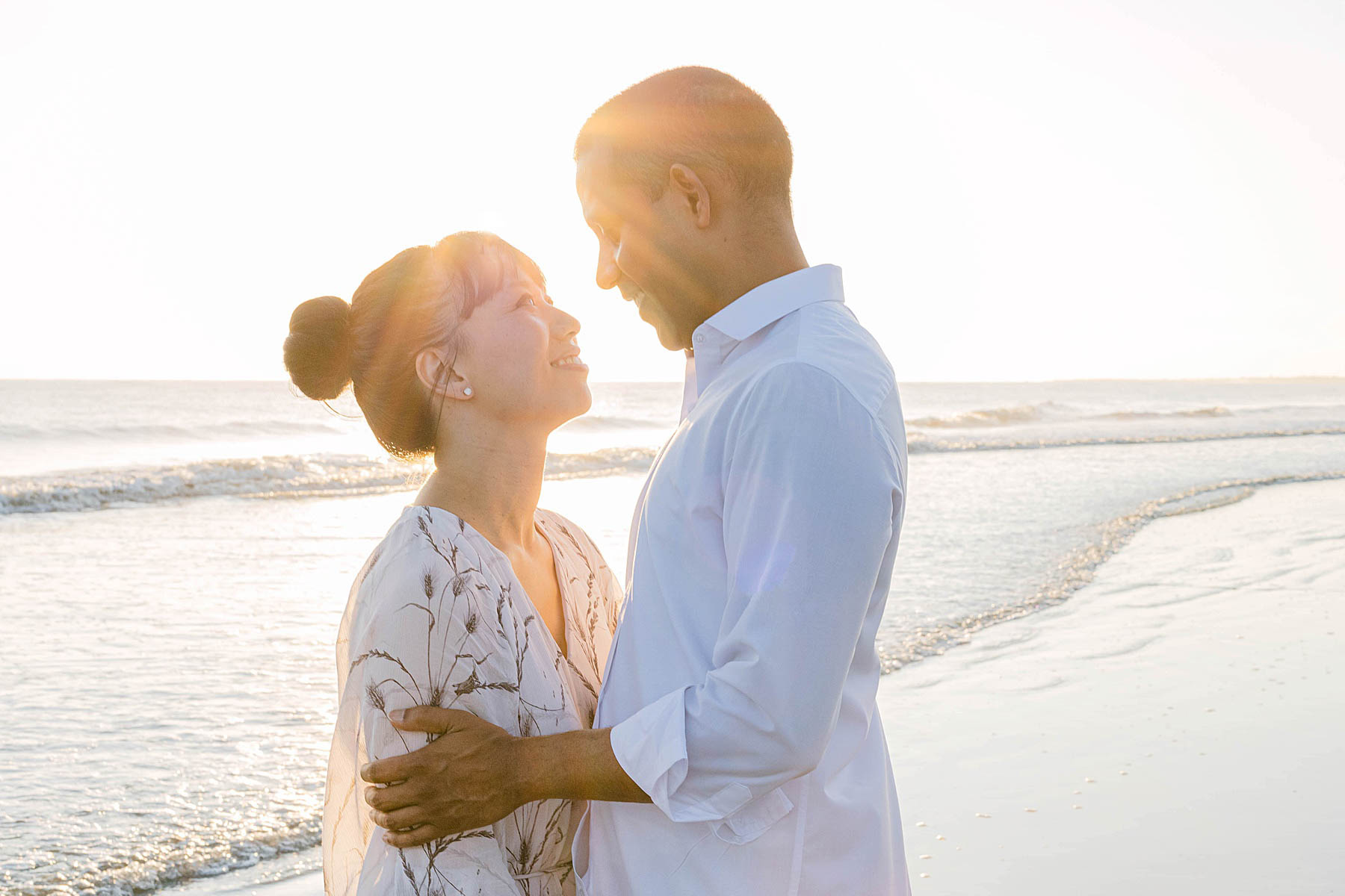 man and woman standing together at sunrise on the beach