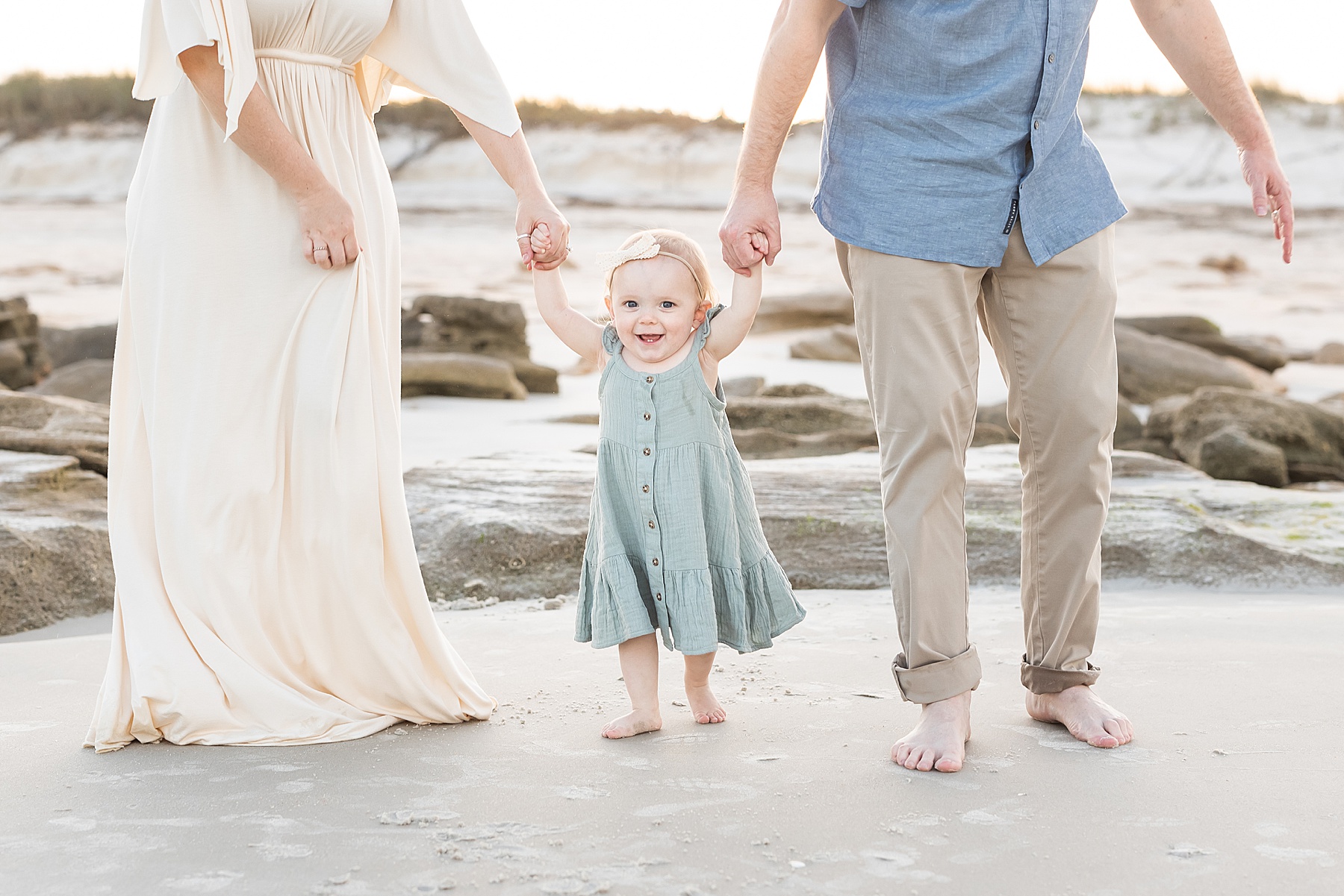 man and woman holding hands with little girl walking on the beach