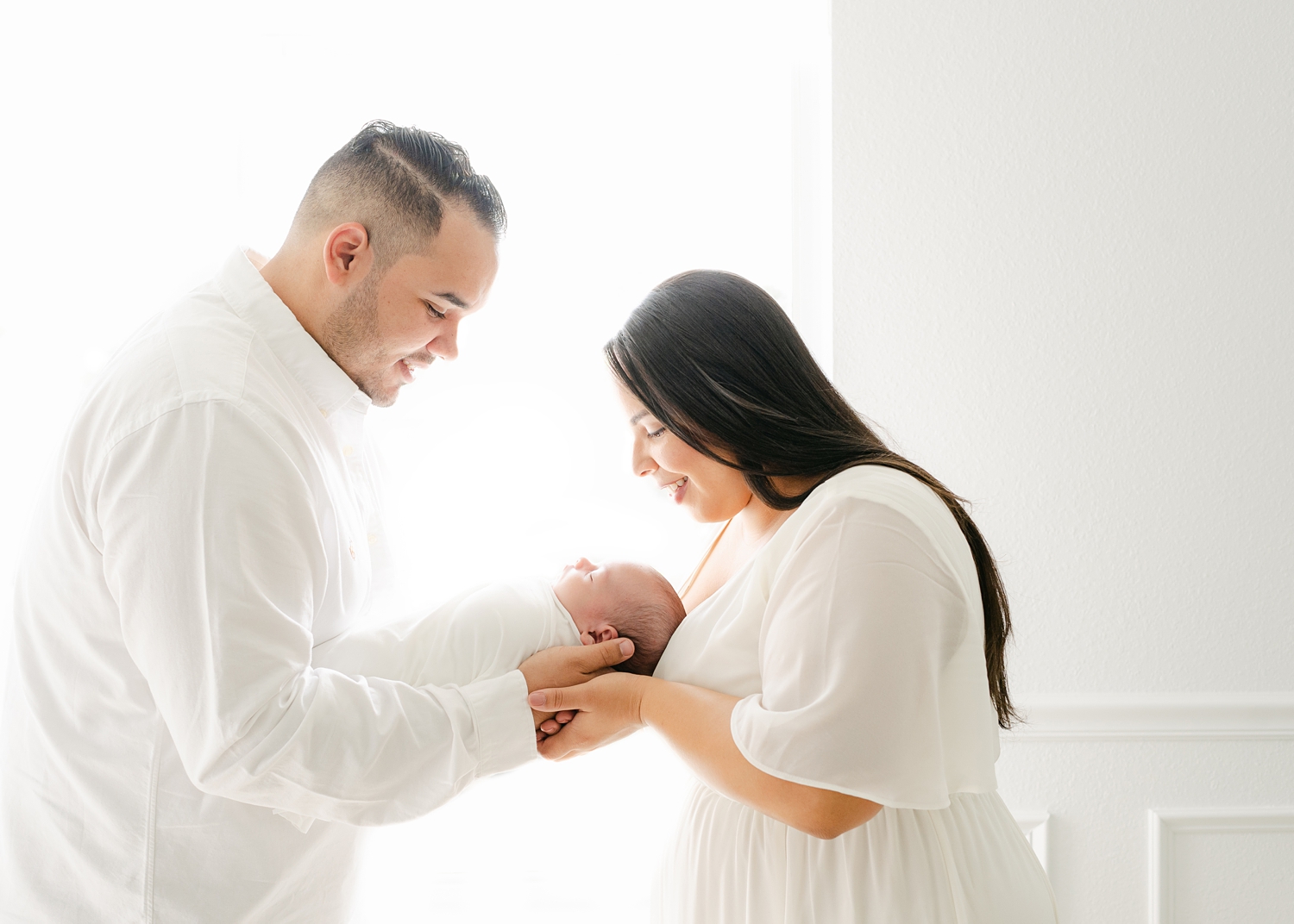 man and woman holding baby boy dressed in white