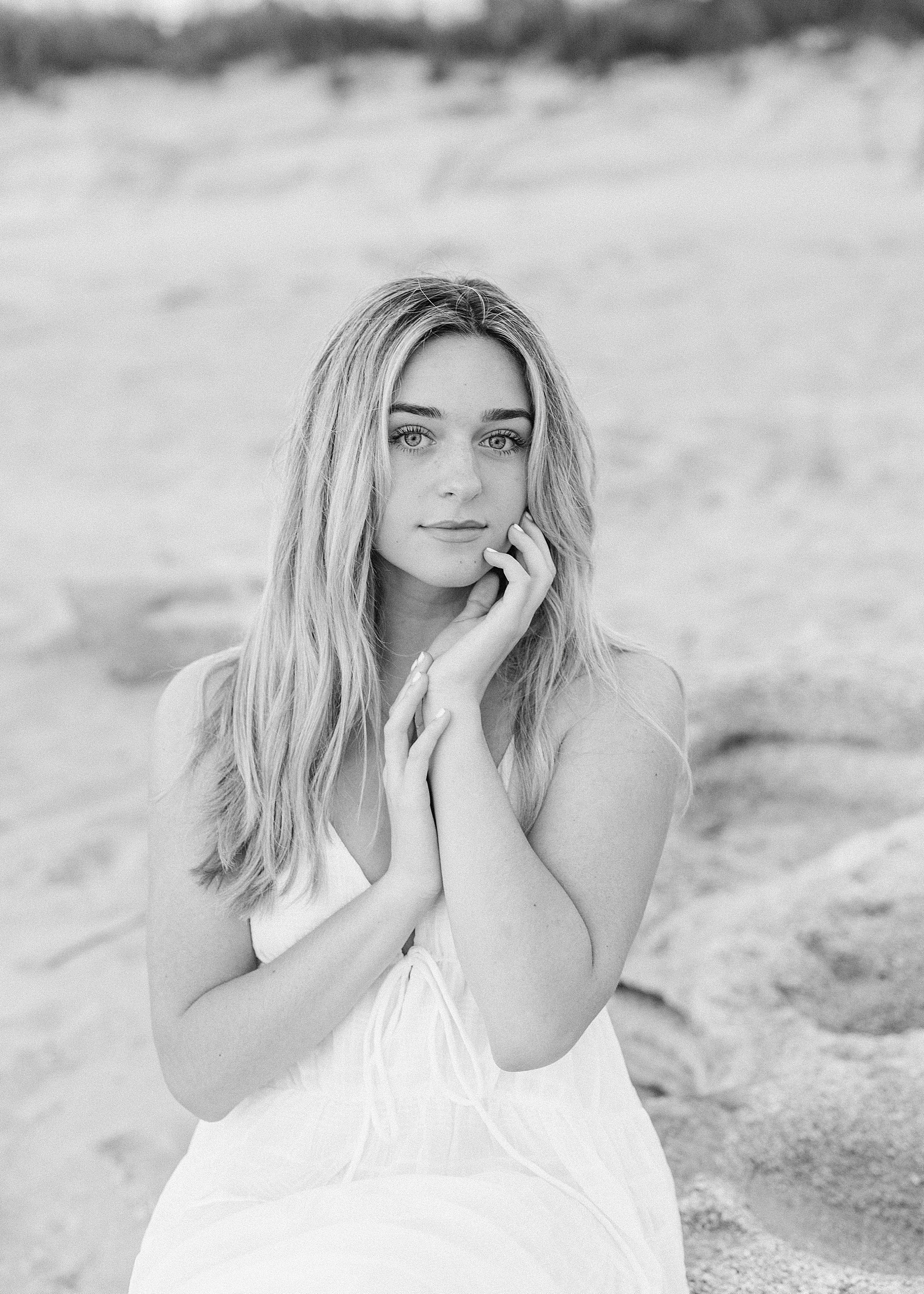 black and white photograph of young woman on the beach at sunrise in long white maxi dress