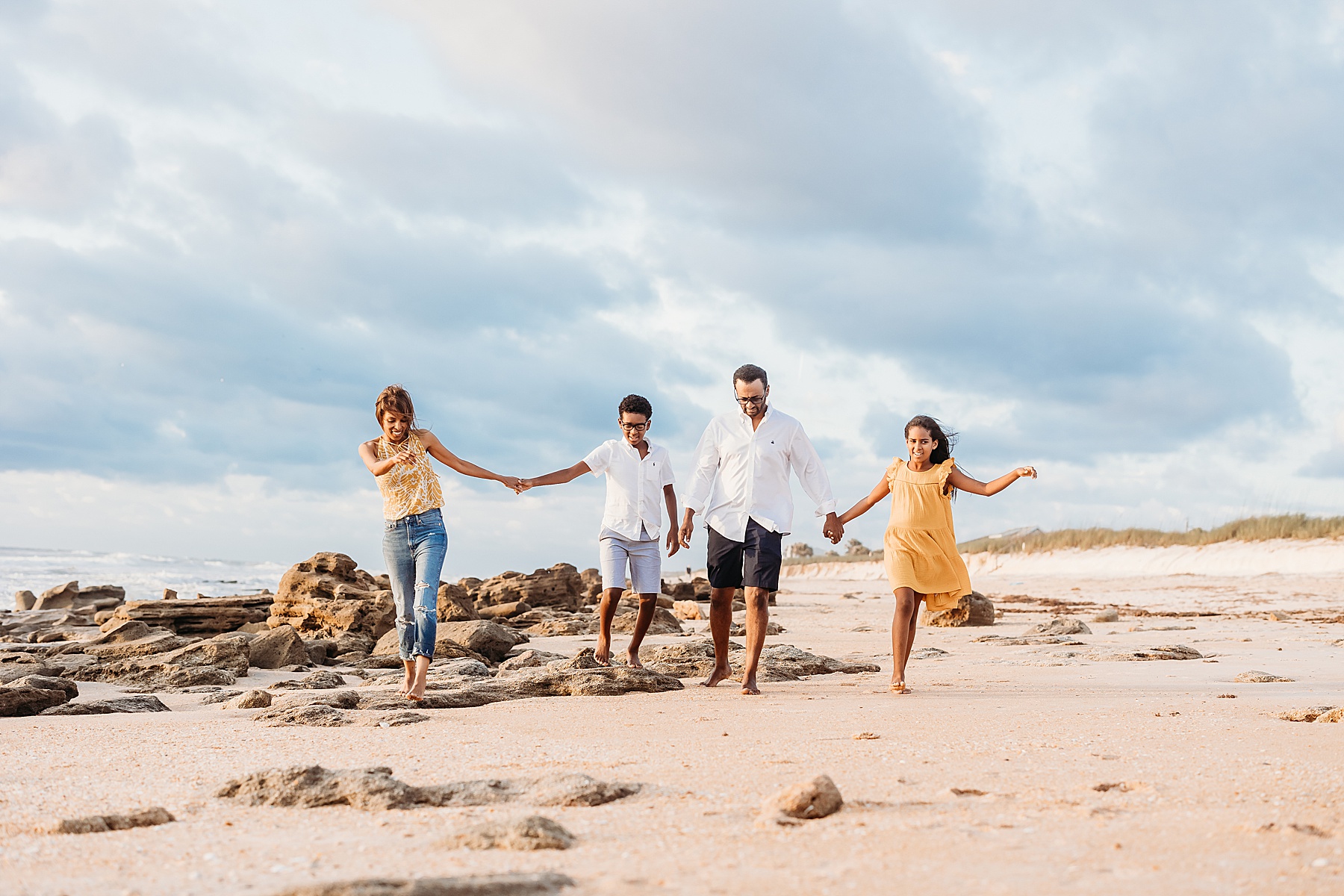 family of four walking on the beach wearing yellow and blue