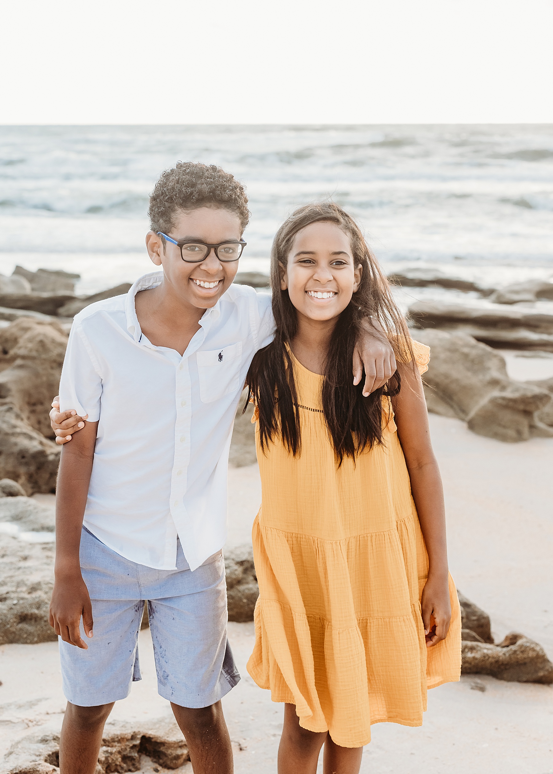 two black children standing on the beach at the rocks 