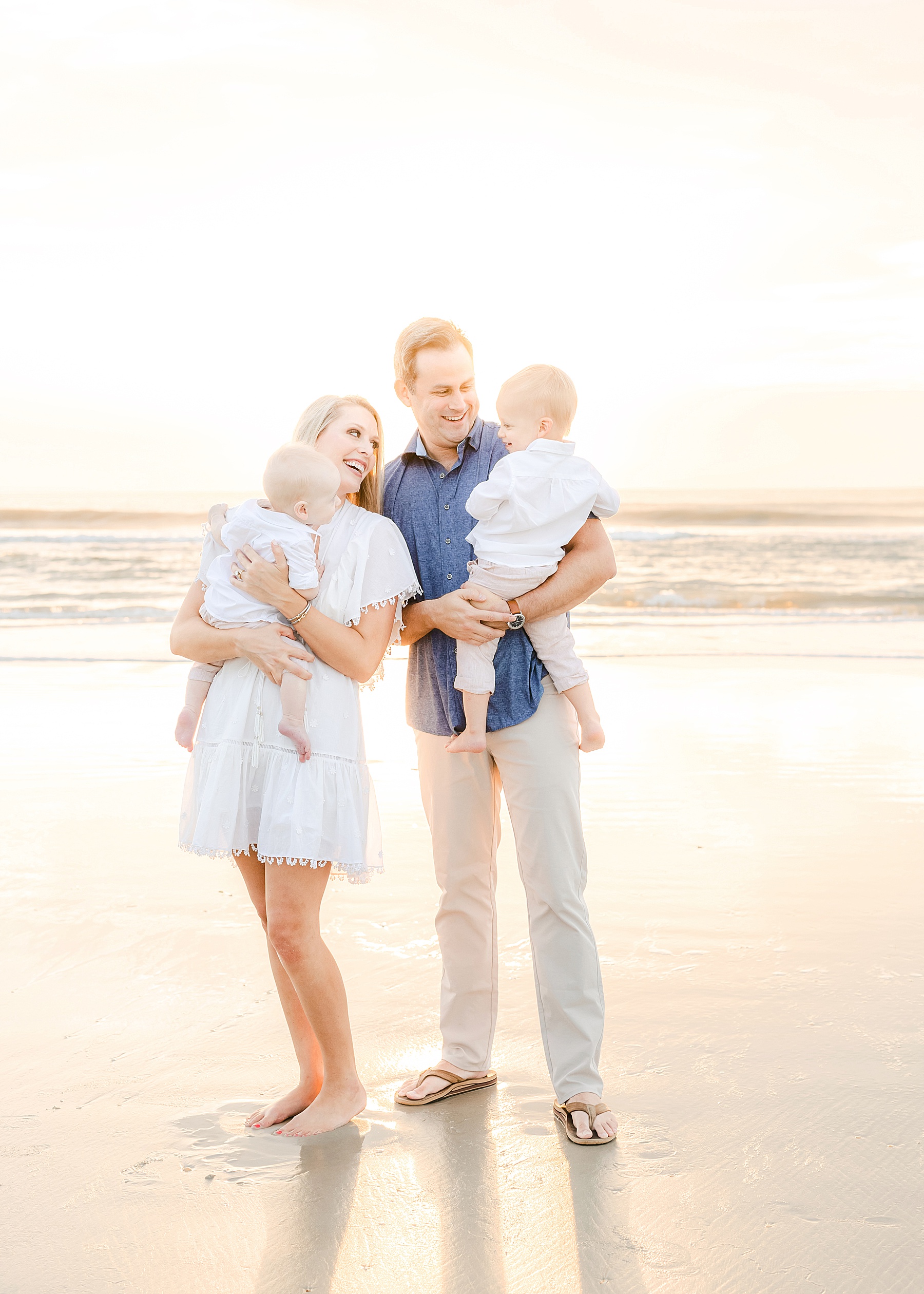 family of four standing on the beach at sunrise in st. augustine florida light and airy clothing