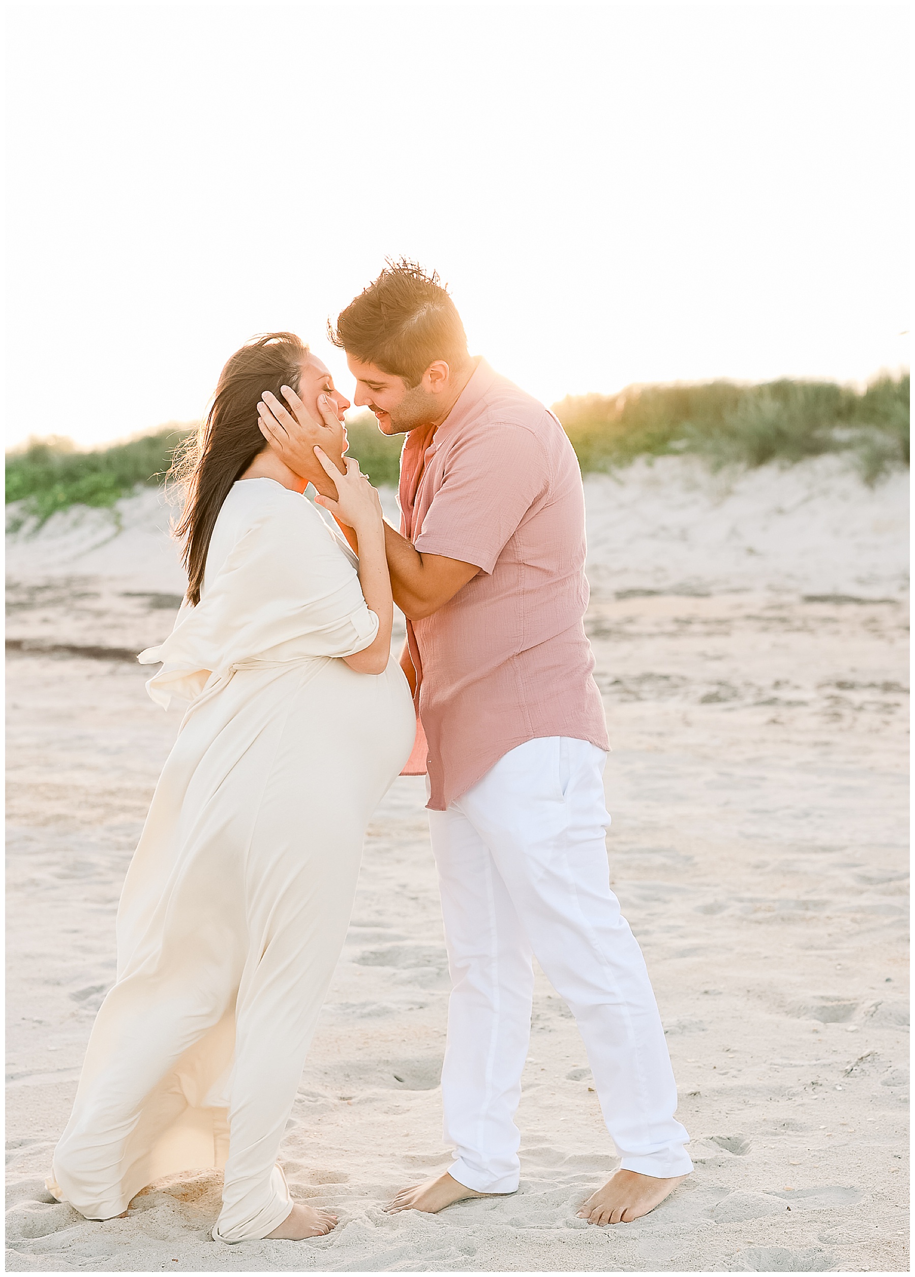 pregnant couple kissing each other on the sand at sunset in Florida