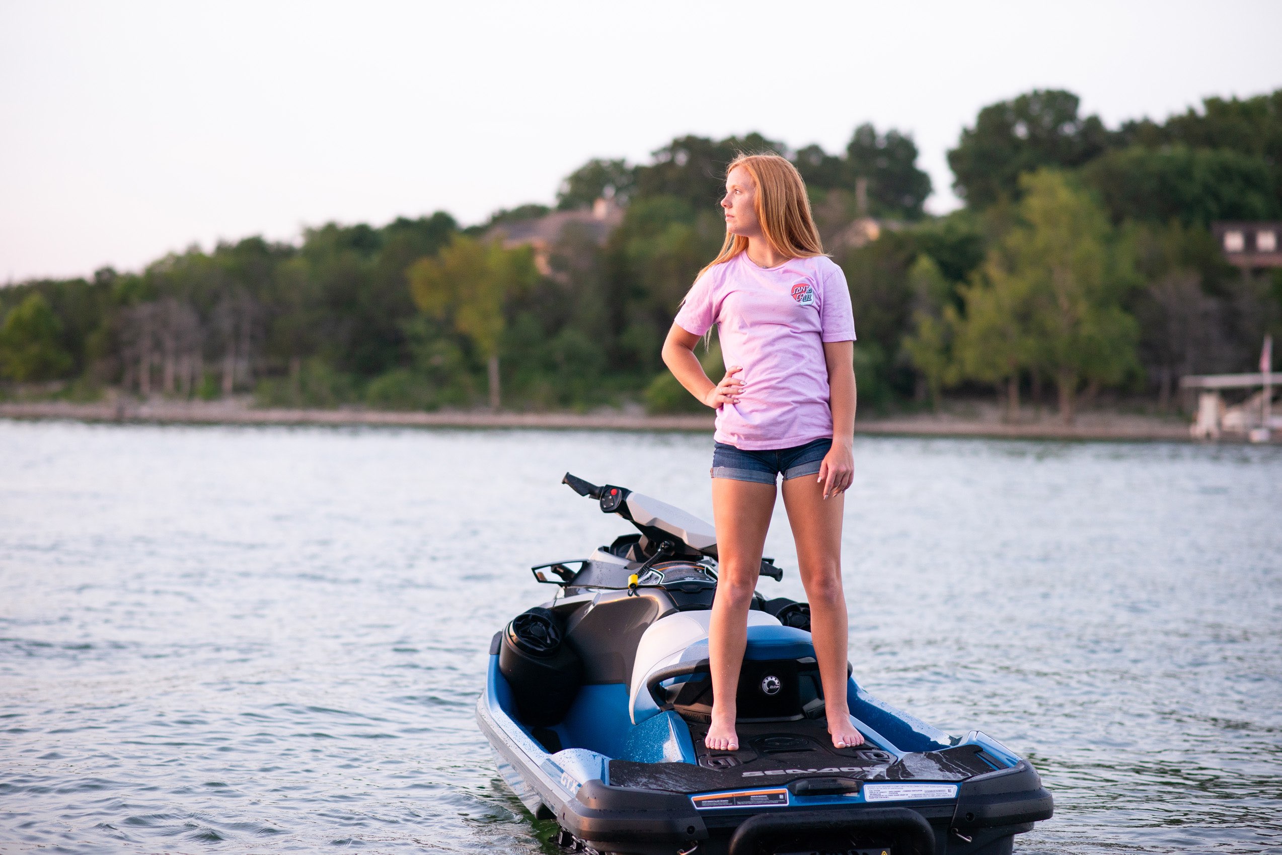 Senior girl in pink tshirt standing on a jet ski at sunset on Tablerock Lake. 