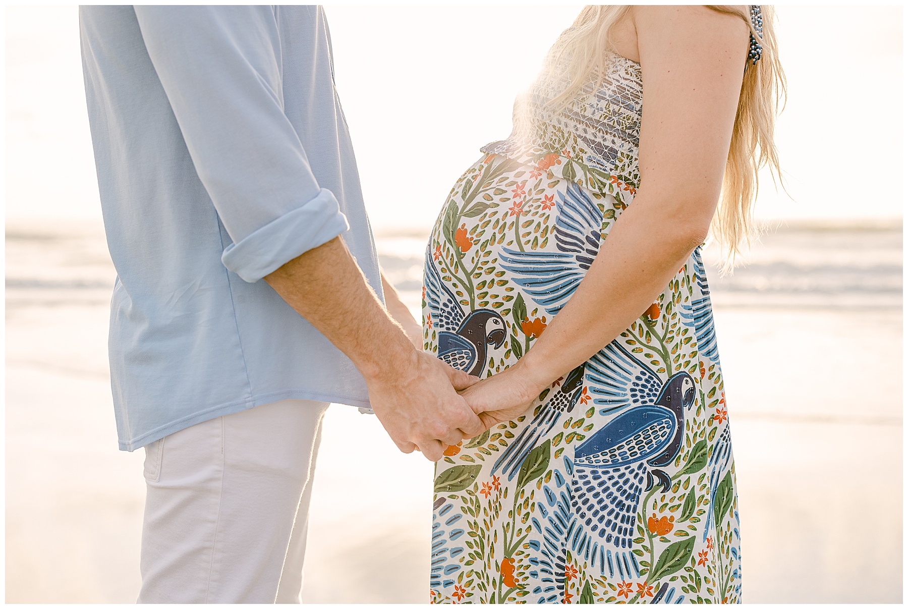 maternity portait of man and woman holding hands on the beach at sunrise in saint augustine beach florida