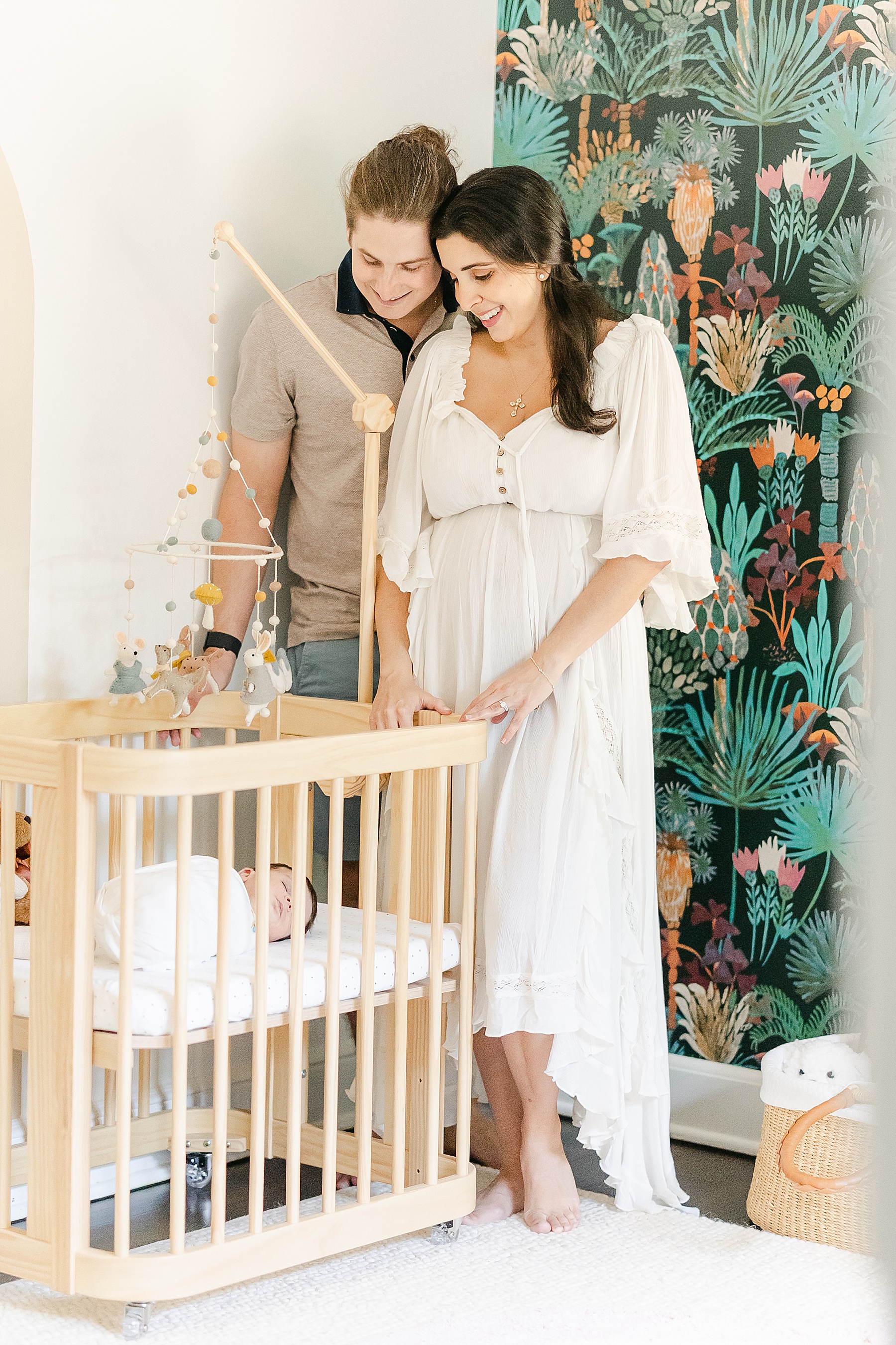 man and woman standing in boho nursery next to neutral crib