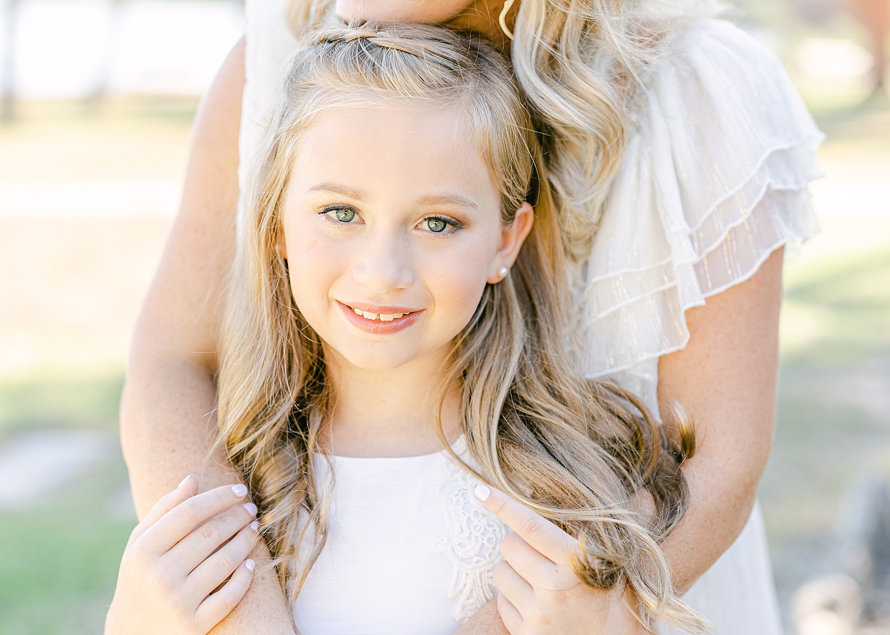 little girl with curled hair dressed in white holding her mom