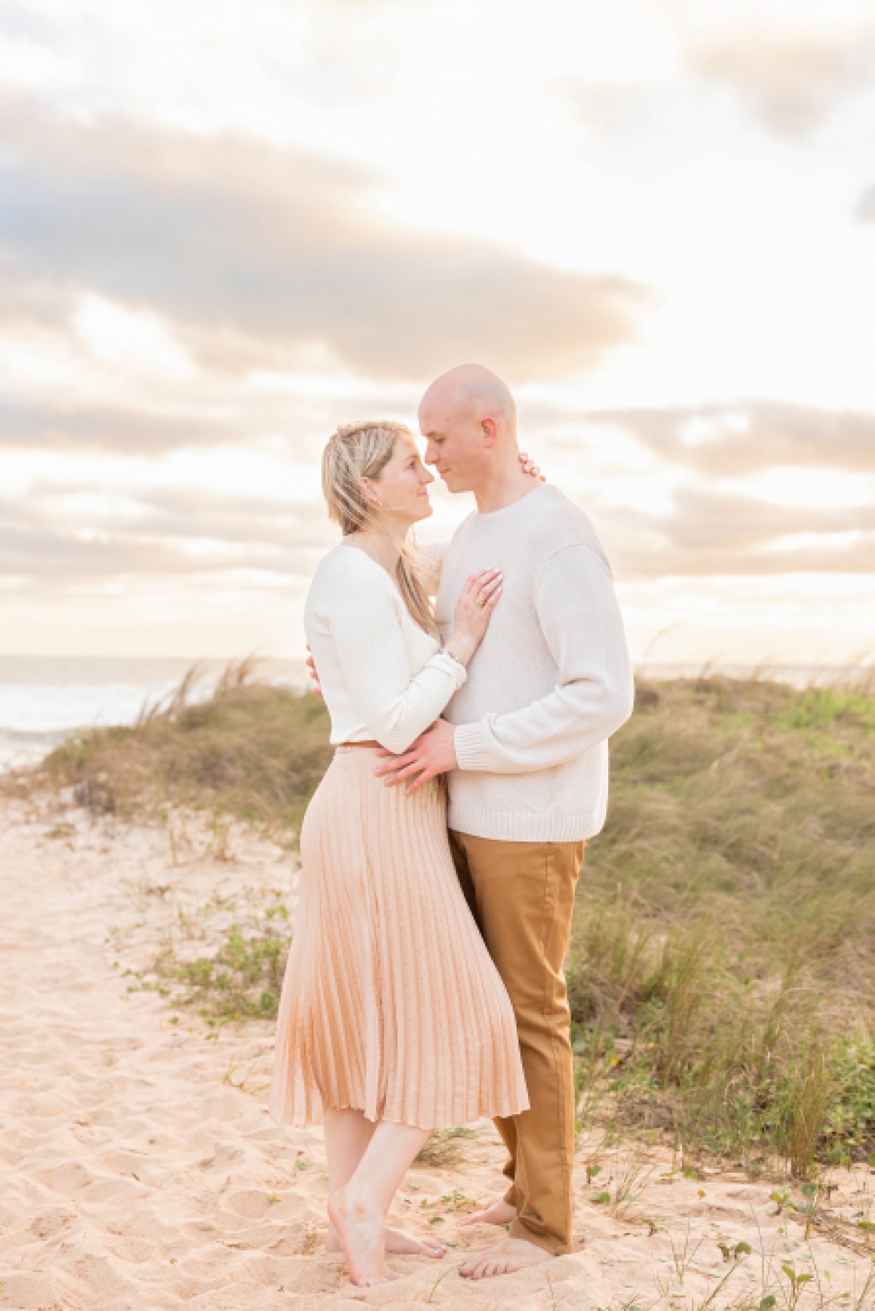 couple standing together on the coast at sunrise