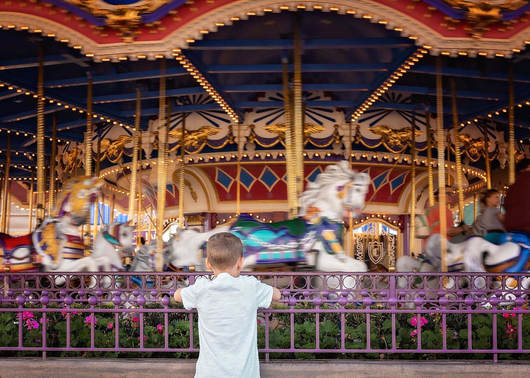 little boy standing in front of a carousel at Walt Disney World Castle 