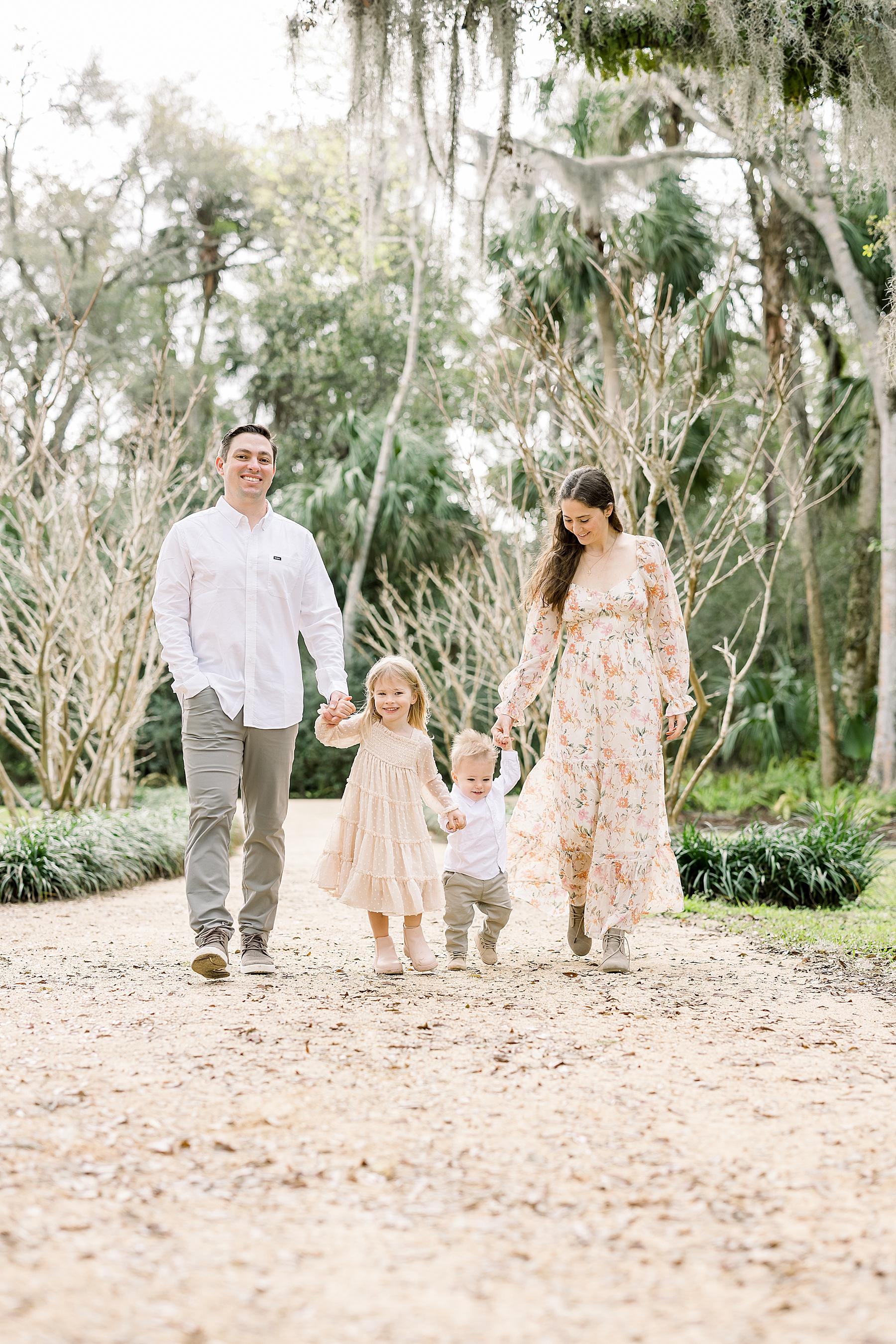 family of four walking in the springtime in florals and neutral clothing at Washington Oaks Gardens State Park