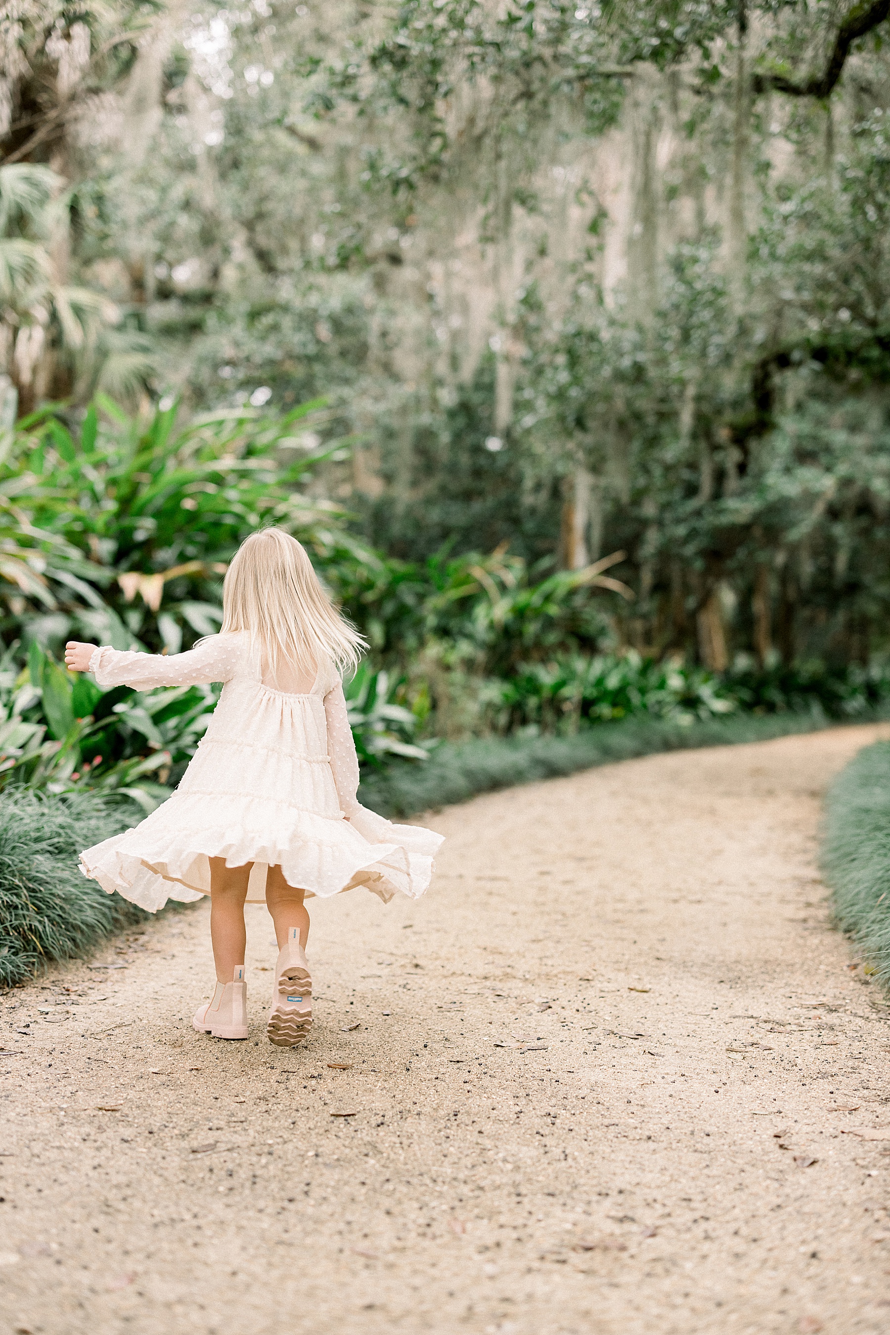 little girl in a floral dress walking down a dirt path at Washington Oaks Gardens State Park in the springtime