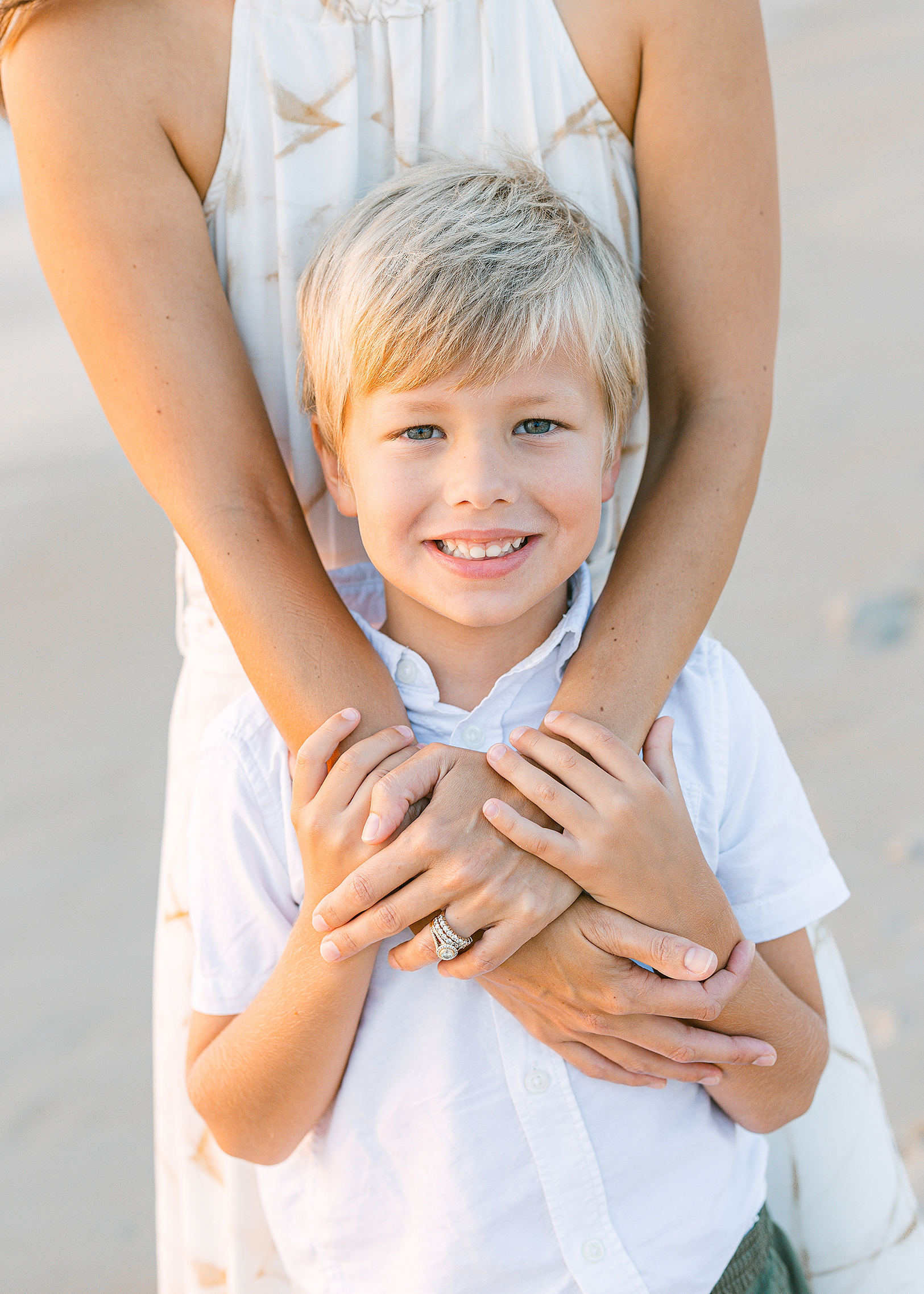 Little blonde haired boy standing with Mother on the beach in St. Augustine Florida.