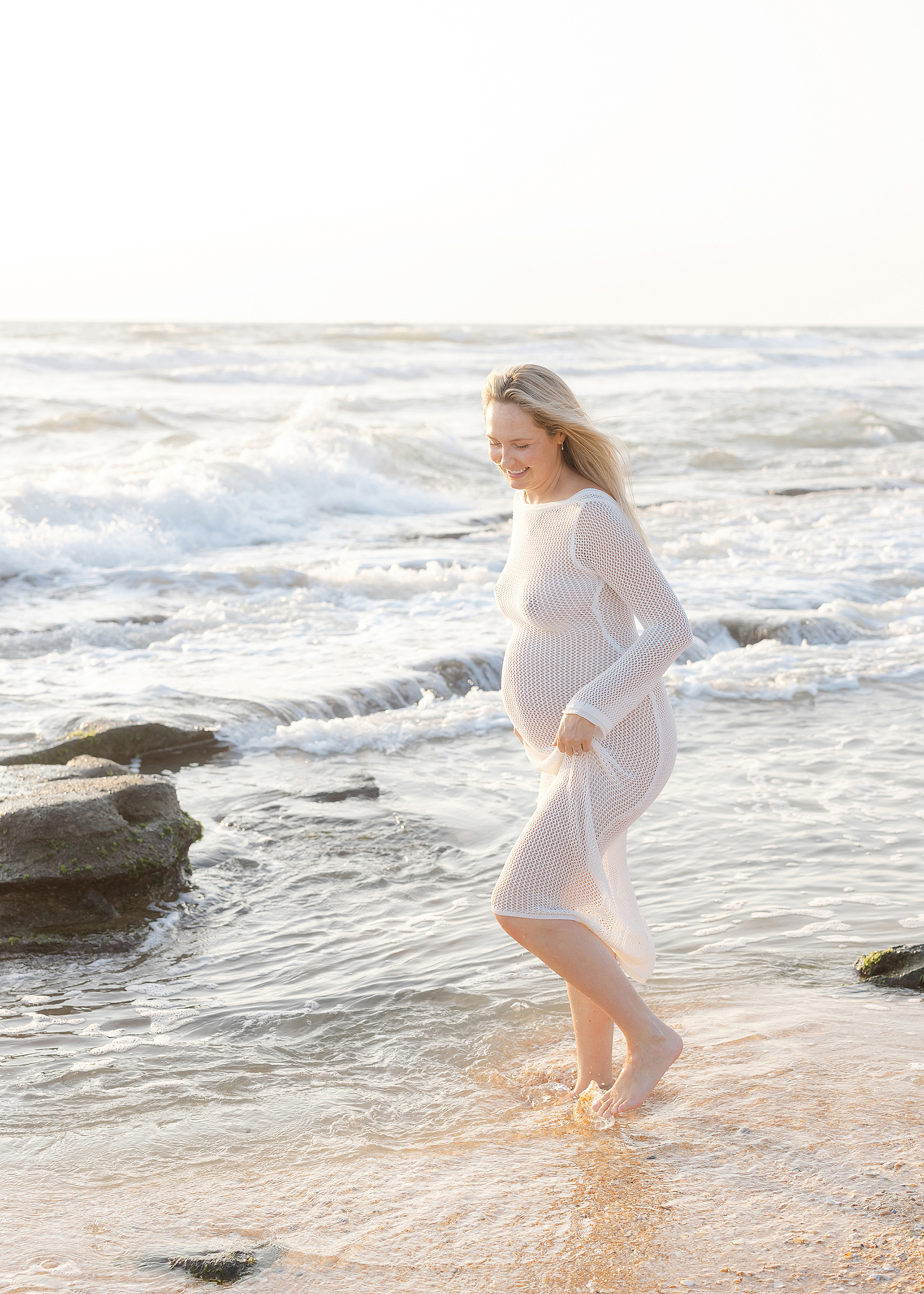 Pregnancy portrait on the beach at sunrise with a white fishnet dress.