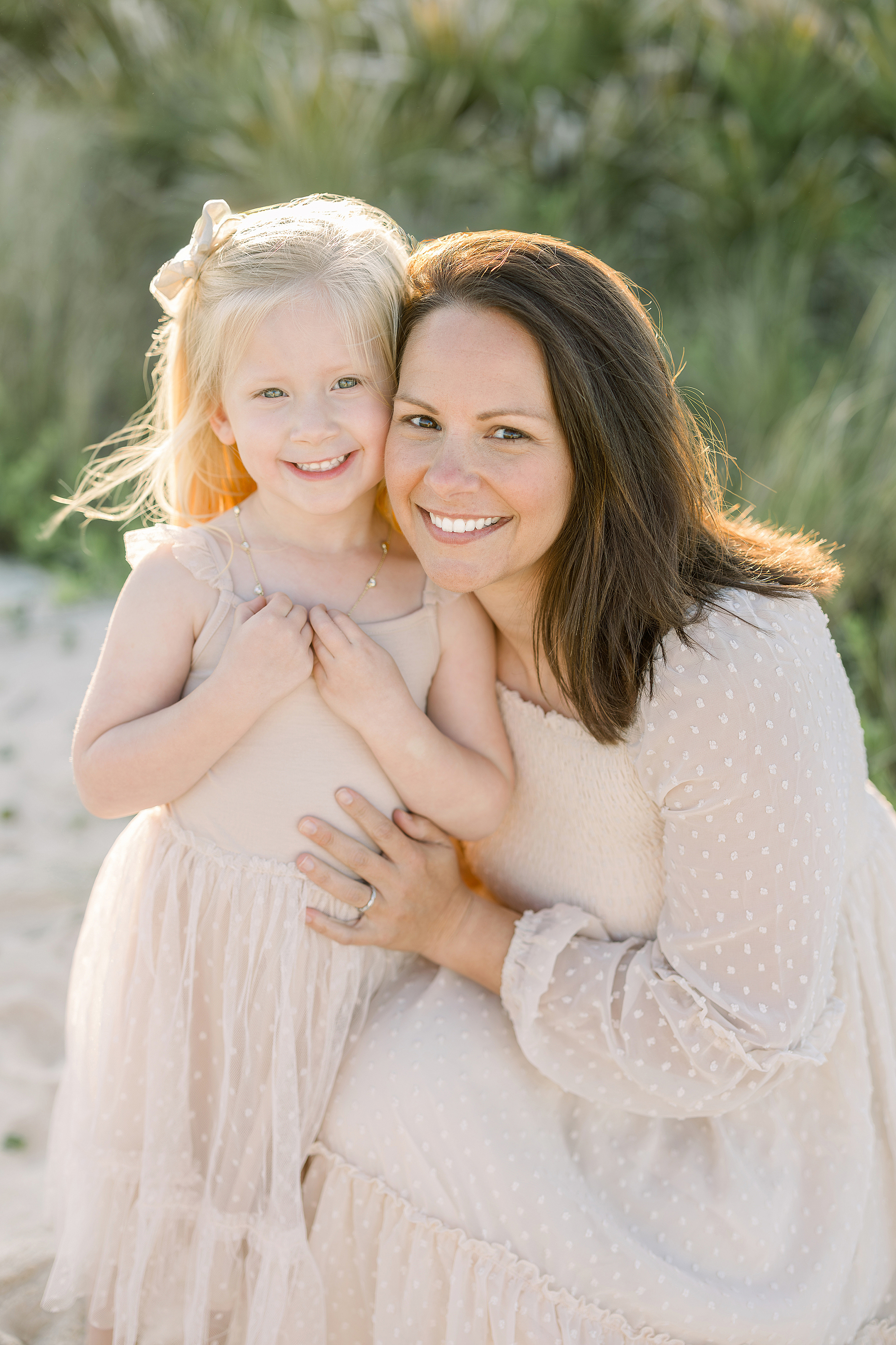 A motherhood beach portrait of a little girl with her mother at the beach at sunset.