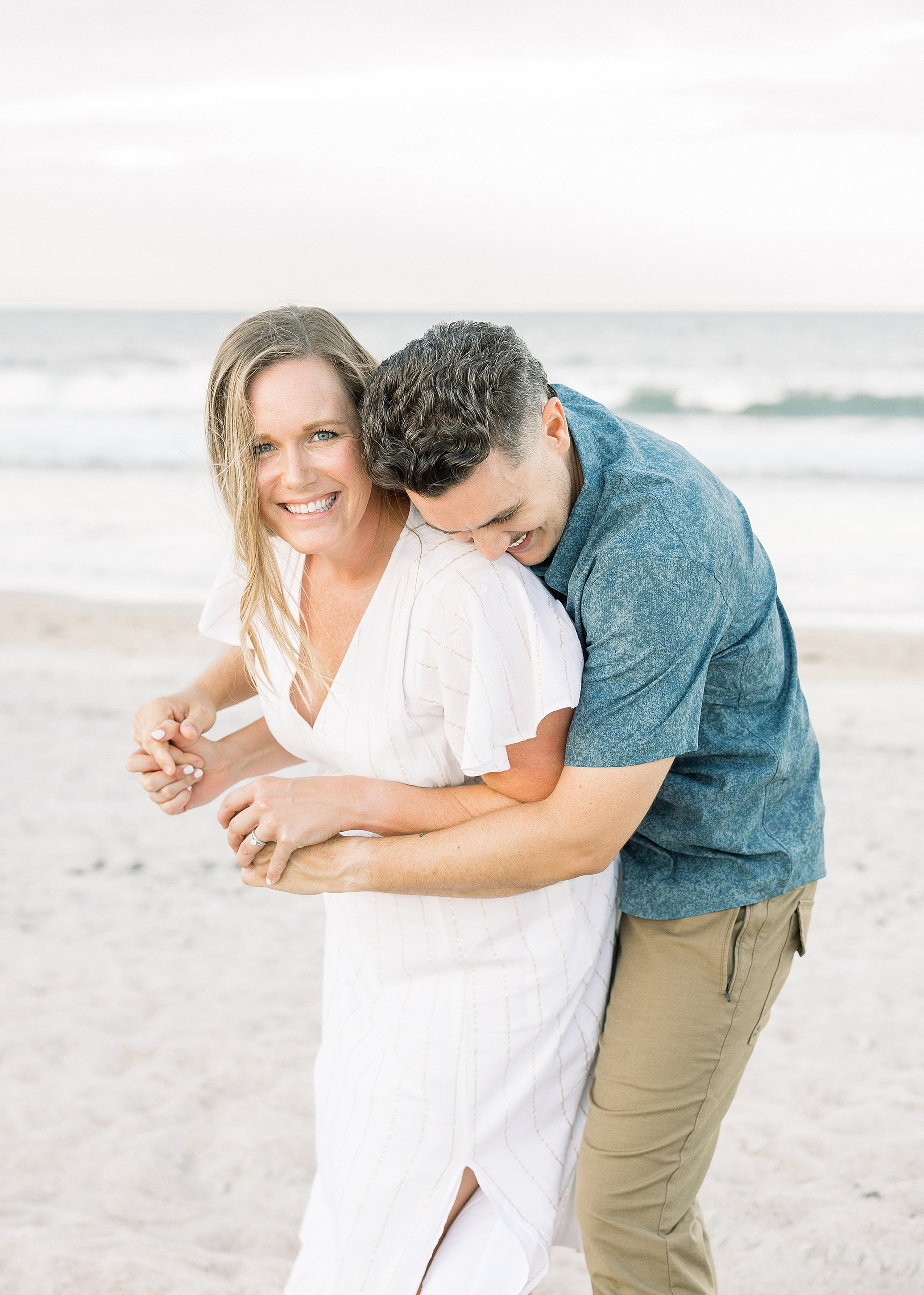 A man and woman playfully hug each other on St. Augustine Beach.