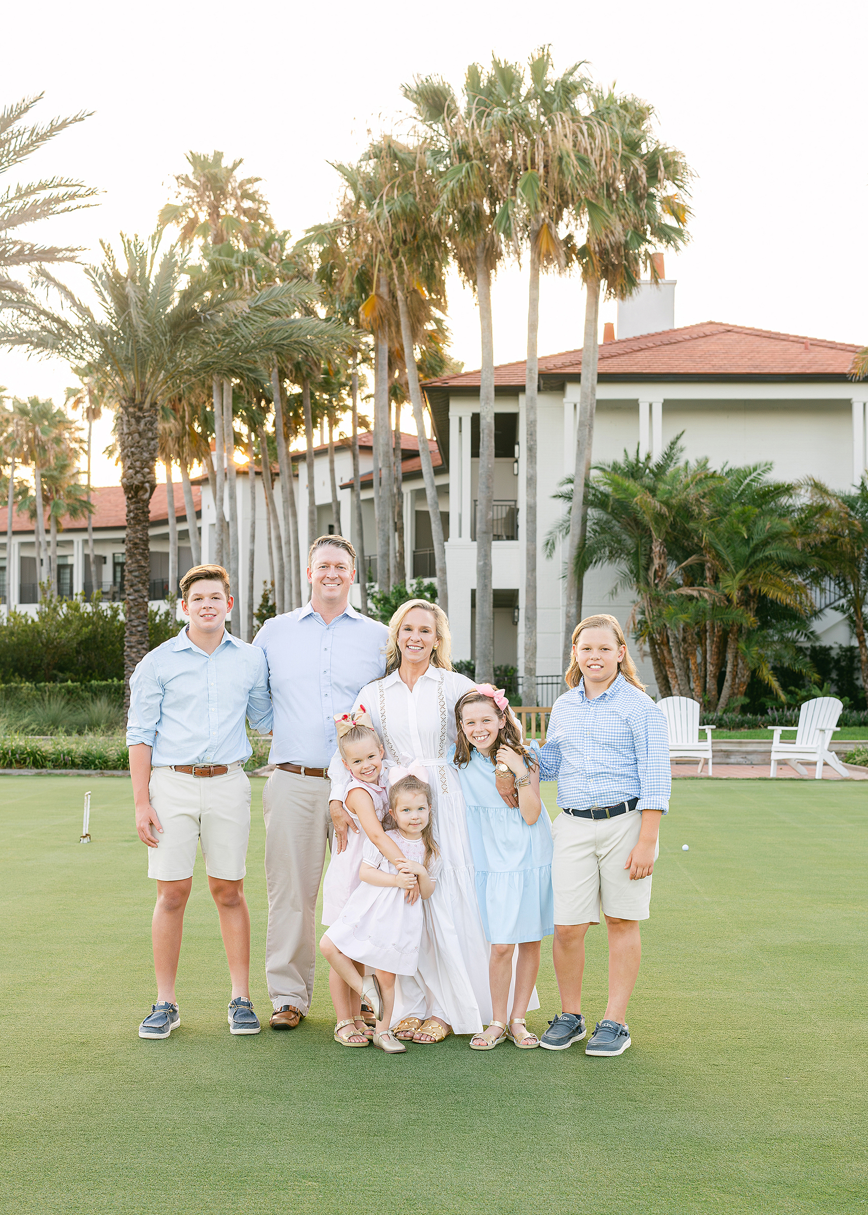 A family sits on a bench at sunset on the golf course.