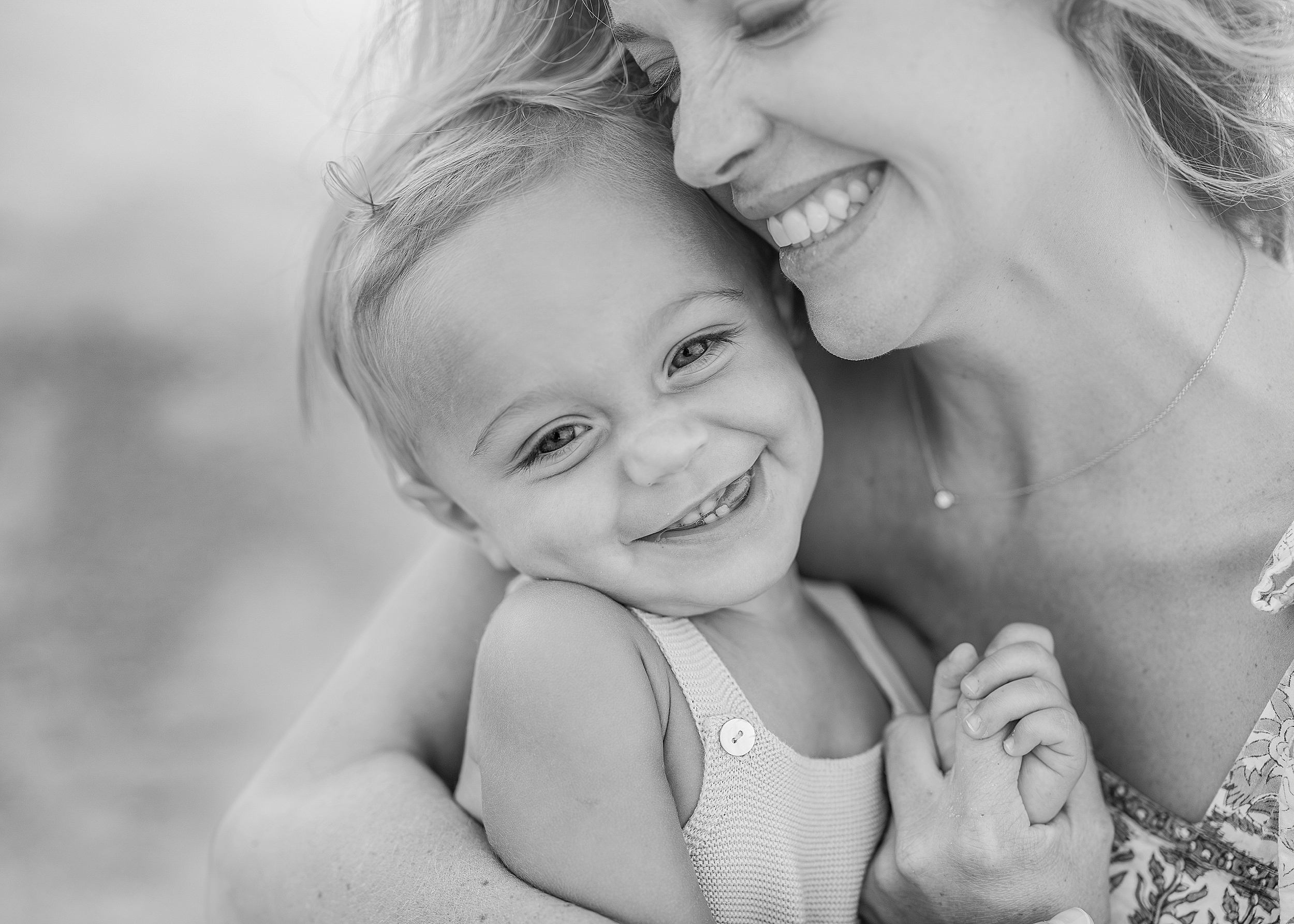 A black and white close up portrait of a mother with her one year old baby boy.